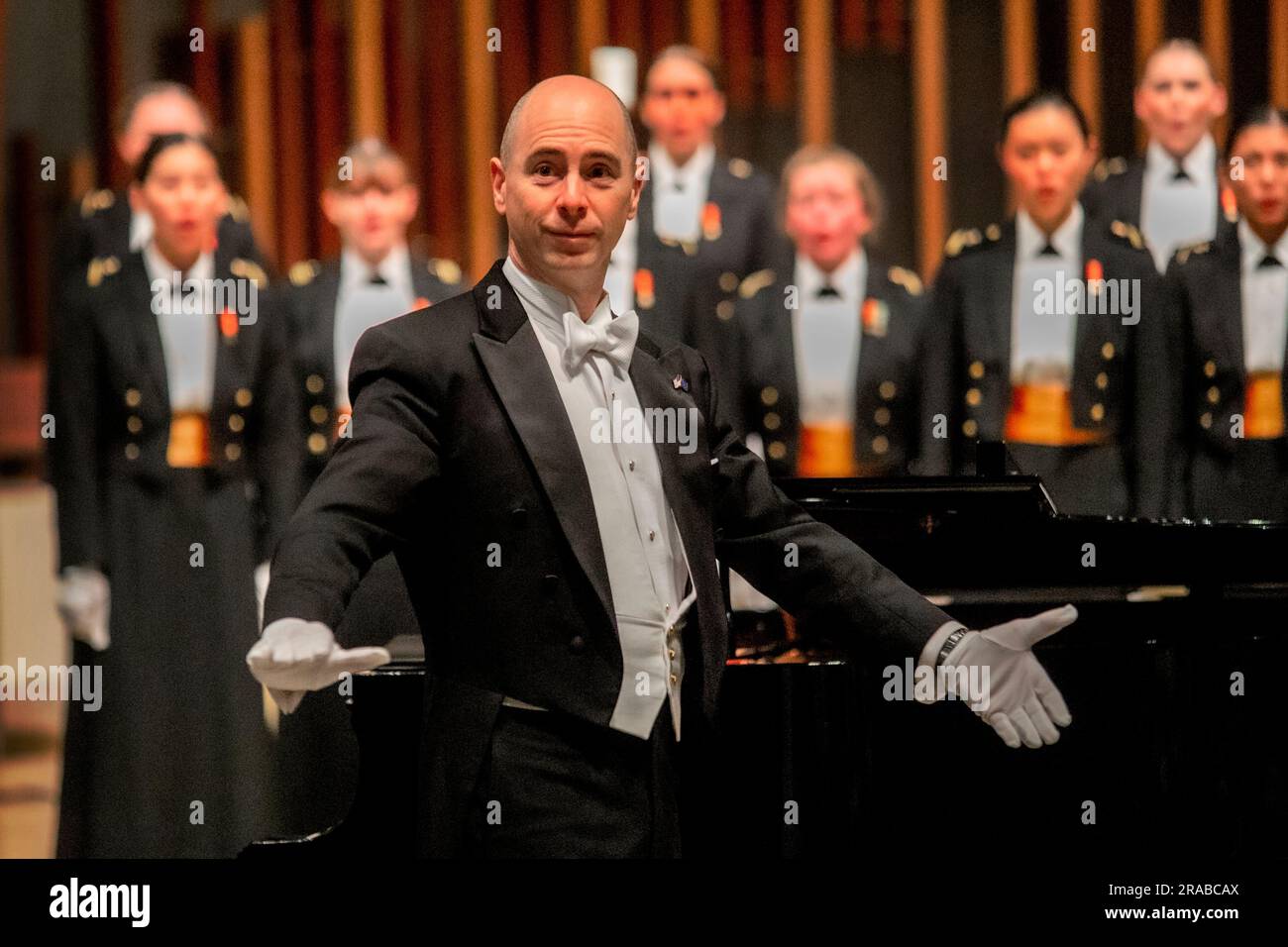 Il direttore formalmente vestito del club US Naval Academy Glee presenta i suoi cantanti ad un concerto a Newport Beach, CALIFORNIA. Foto Stock