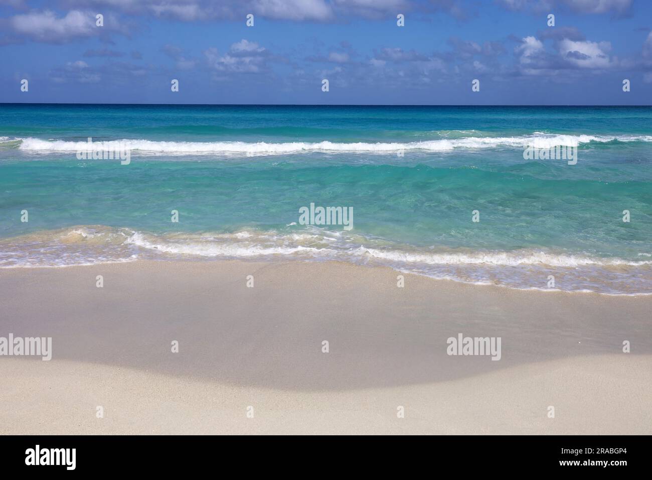 Spiaggia di mare vuota con sabbia bianca, vista delle onde azzurre e del cielo blu con le nuvole. Costa caraibica, sfondo per vacanze in una natura paradisiaca Foto Stock