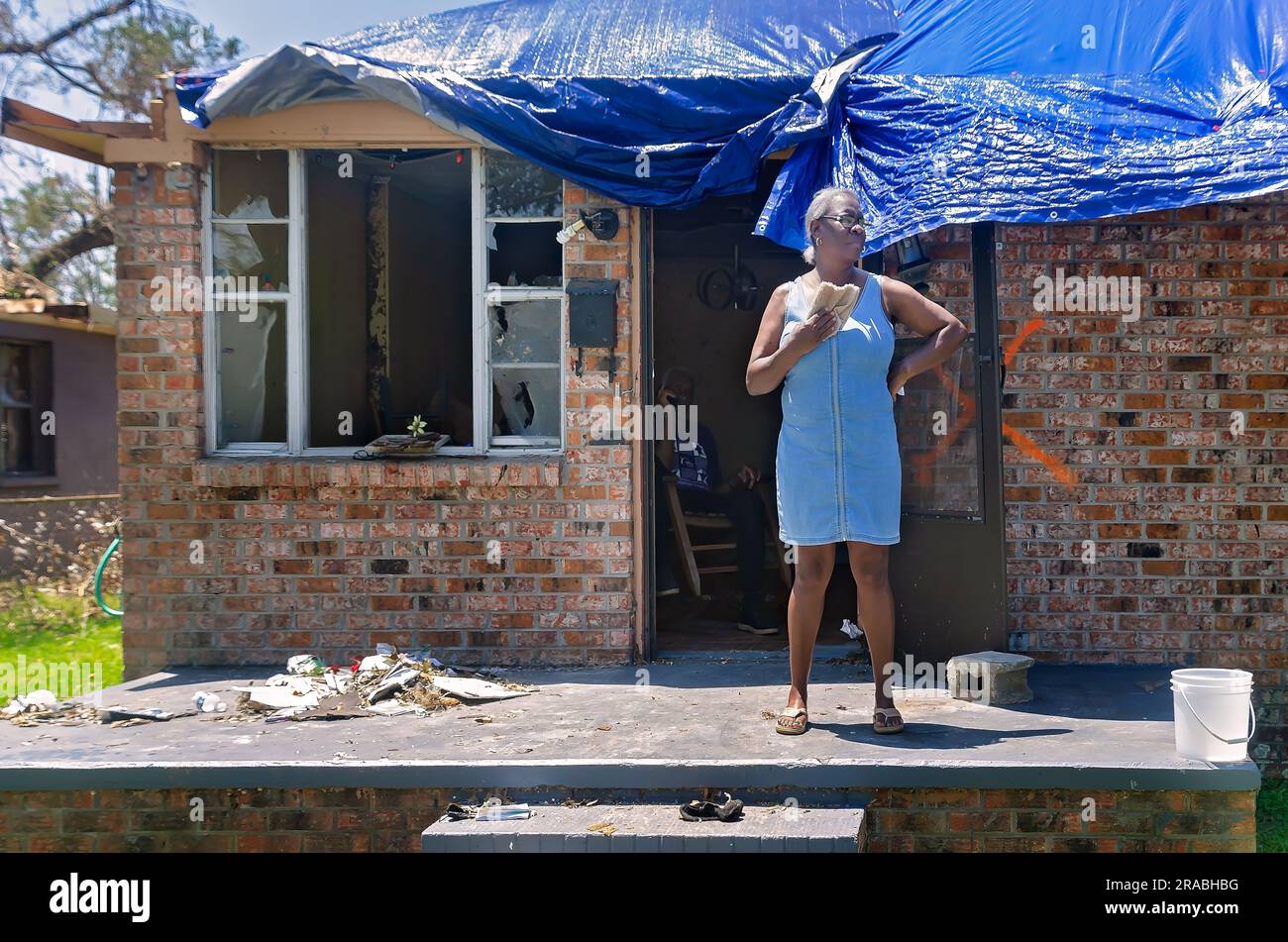 Dorine Watson Lynn si tira fuori con un panno da lavaggio mentre si trova sul portico della sua casa devastata da tornado, il 28 giugno 2023, a Moss Point, Mississippi. Foto Stock