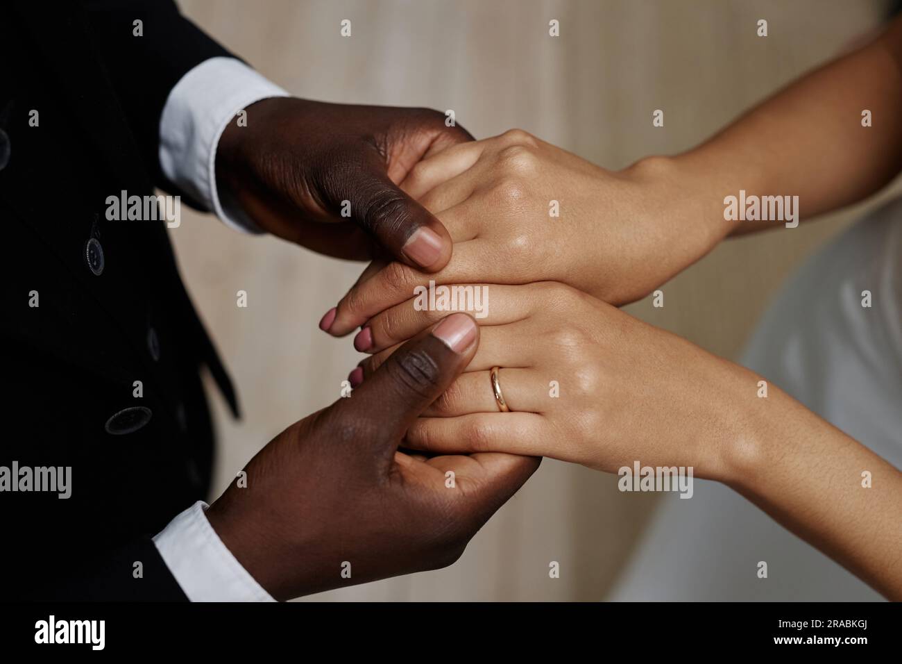 Primo piano della giovane coppia nera che si sposa con la sposa e lo sposo che si tiene per mano, concentrati sulle fedi nuziali Foto Stock
