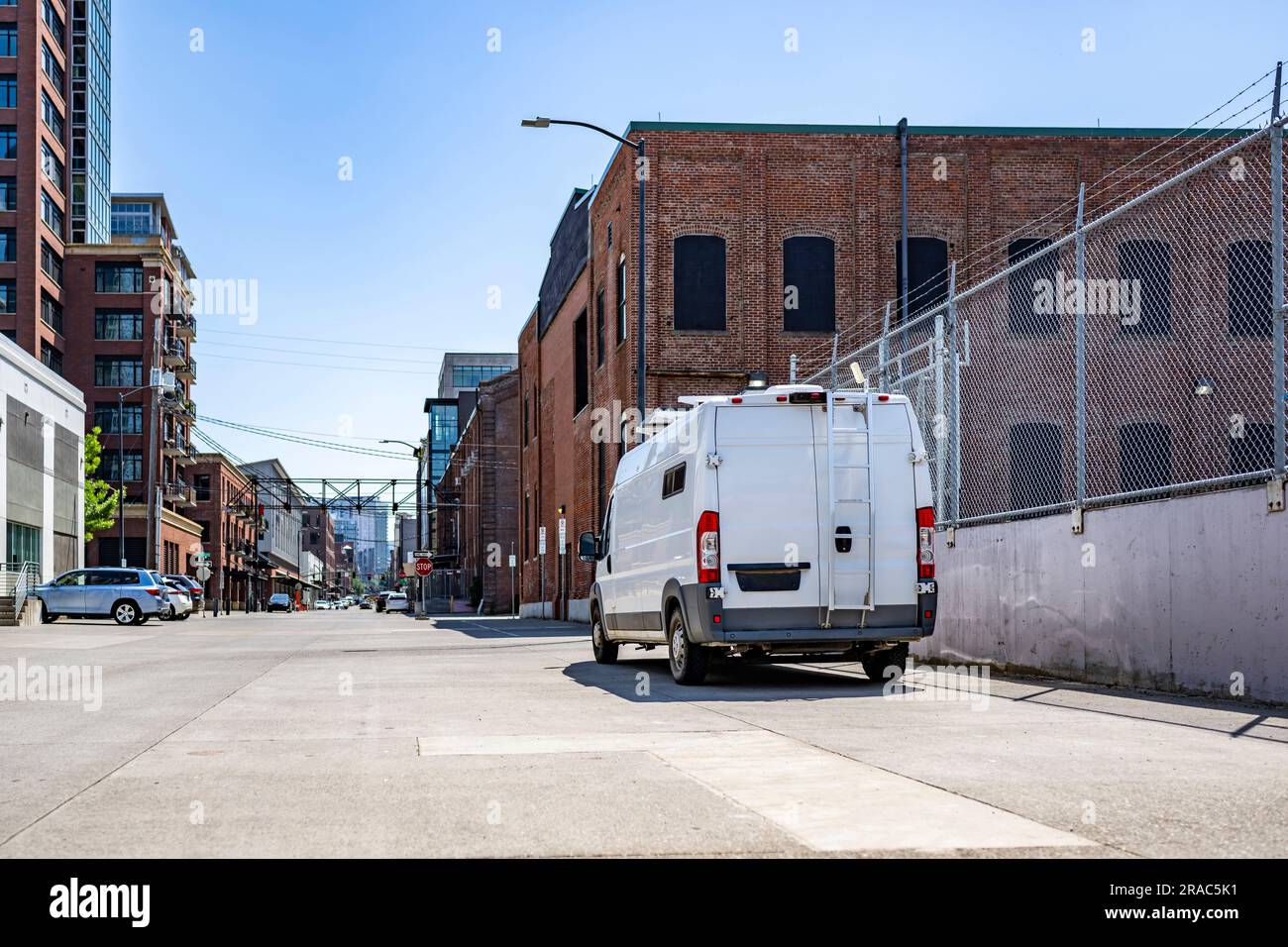 Mini van cargo economico, compatto e maneggevole, bianco, per consegne locali, scarico merci consegnate in piedi sulla strada urbana con Foto Stock