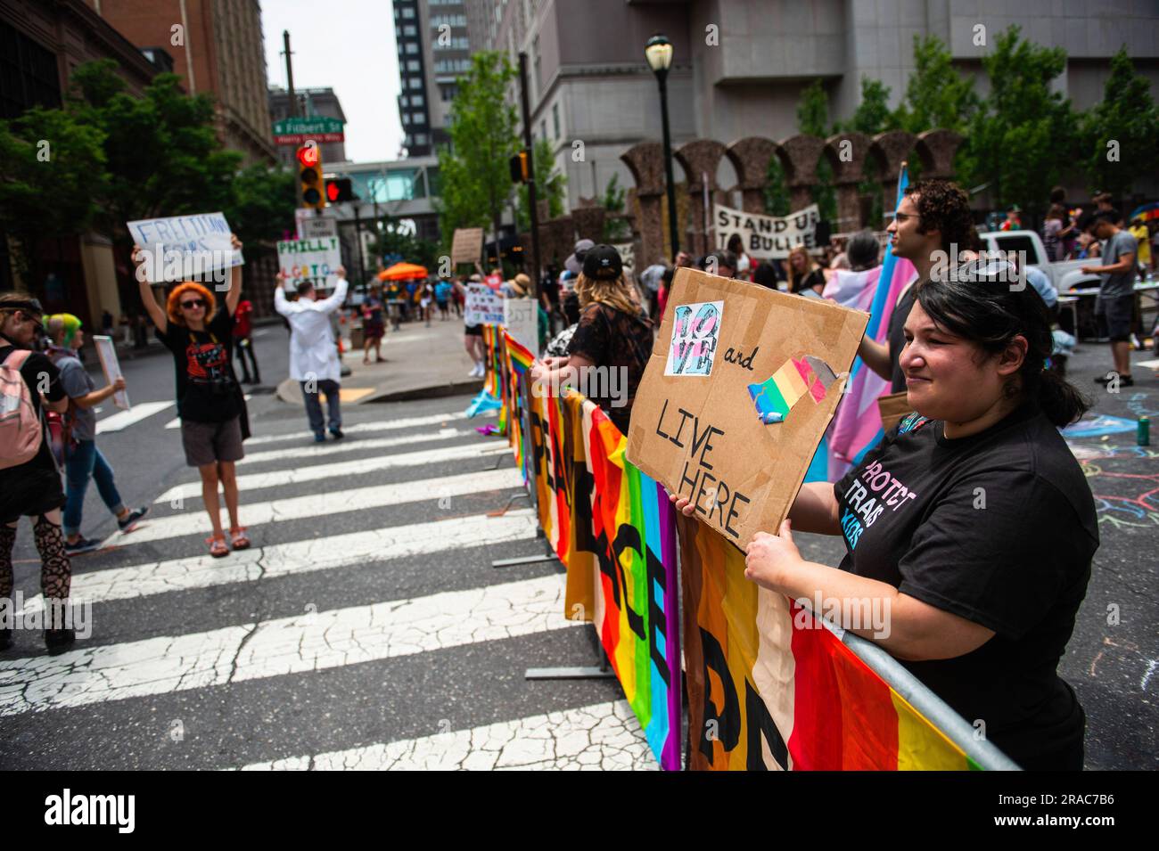 I manifestanti tengono cartelli e bandiere ondulate durante una protesta tenuta dal movimento dei bambini Philly contro Moms for Liberty nel centro di Philadelphia. MUM's for Liberty, un gruppo del 2021 per combattere i mandati COVID-19, tenne il loro summit annuale a Philadelphia, in Pennsylvania, e furono incontrati da manifestanti che protestavano contro l'evento e le azioni di Mom's for Liberty. Il gruppo che è designato dal Southern Poverty Law Center come gruppo di odio, è stato una voce vocale nella retorica anti-LGBT e la spinta a vietare alcuni libri dalle scuole e dalle biblioteche. Foto Stock