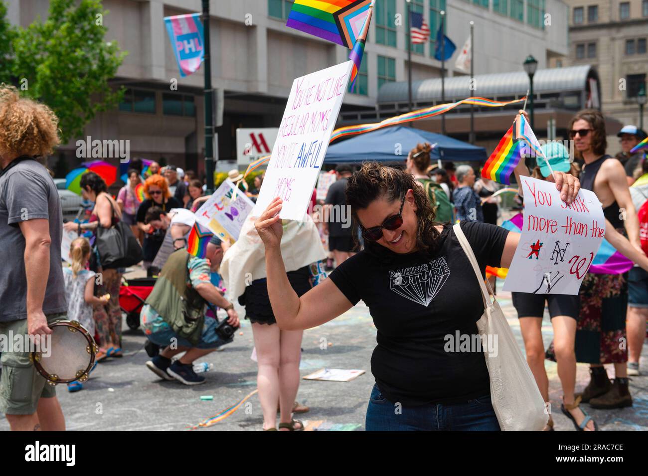 Un manifestante balla con cartelli durante una protesta tenuta dal movimento dei bambini Philly contro Moms for Liberty nel centro di Filadelfia. MUM's for Liberty, un gruppo del 2021 per combattere i mandati COVID-19, tenne il loro summit annuale a Philadelphia, in Pennsylvania, e furono incontrati da manifestanti che protestavano contro l'evento e le azioni di Mom's for Liberty. Il gruppo che è designato dal Southern Poverty Law Center come gruppo di odio, è stato una voce vocale nella retorica anti-LGBT e la spinta a vietare alcuni libri dalle scuole e dalle biblioteche. Foto Stock