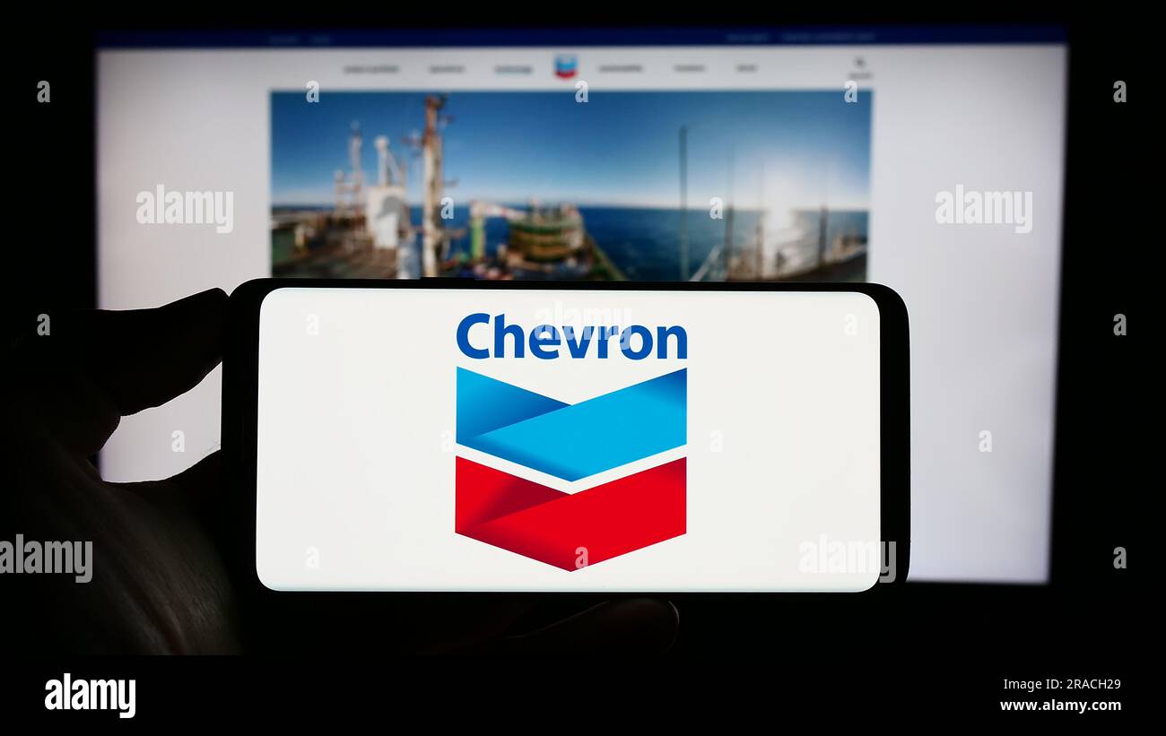 Persona che tiene il cellulare con il logo della società americana di energia Chevron Corporation sullo schermo davanti alla pagina Web aziendale. Concentrarsi sul display del telefono. Foto Stock