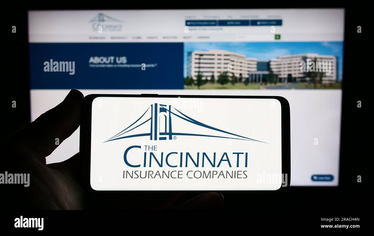 Persona che possiede uno smartphone con il logo della società statunitense Cincinnati Financial Corporation sullo schermo davanti al sito Web. Concentrarsi sul display del telefono. Foto Stock