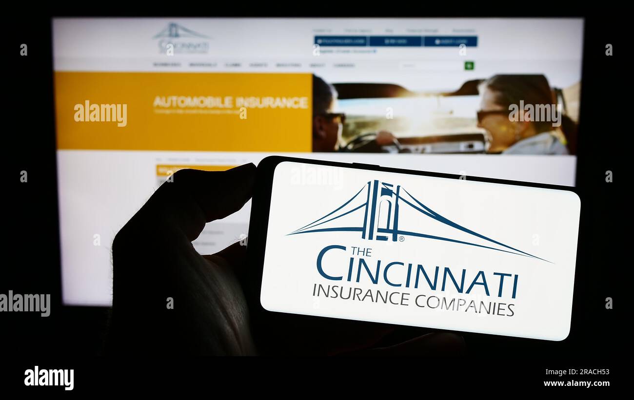 Persona in possesso di un cellulare con il logo della società americana Cincinnati Financial Corporation sullo schermo davanti alla pagina Web. Concentrarsi sul display del telefono. Foto Stock