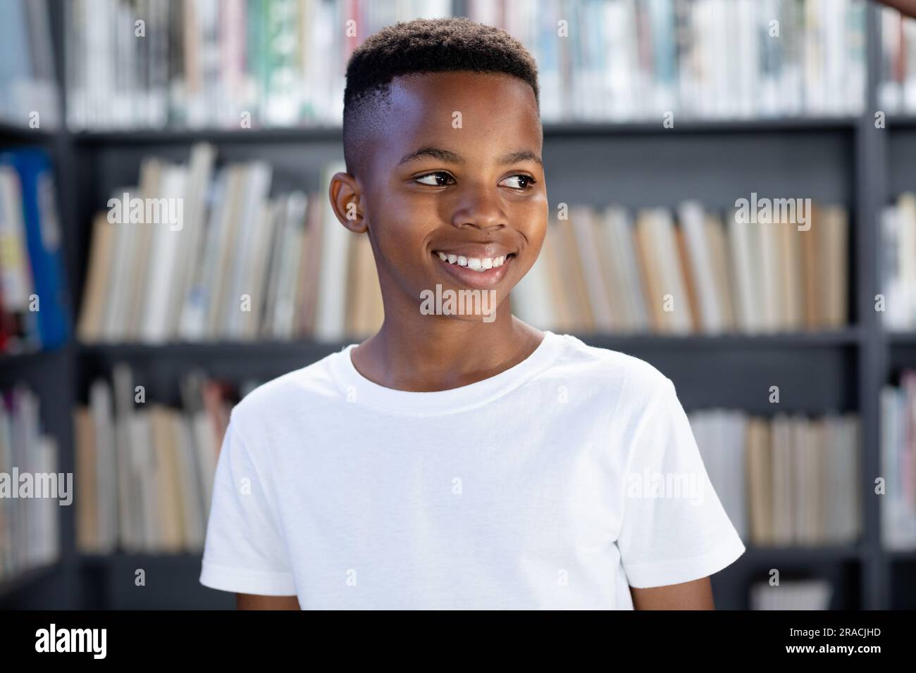 Scolaro afroamericano che indossa una maglietta bianca con spazio copioso sopra la biblioteca Foto Stock