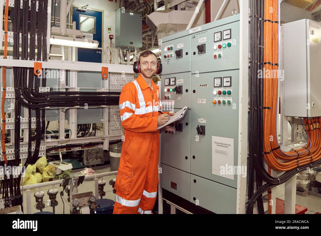 Giovane ingegnere professionista che controlla i parametri della scheda di commutazione ad alta tensione. Ingegnere offshore che effettua controlli sulle apparecchiature elettriche ad alta tensione. Foto Stock