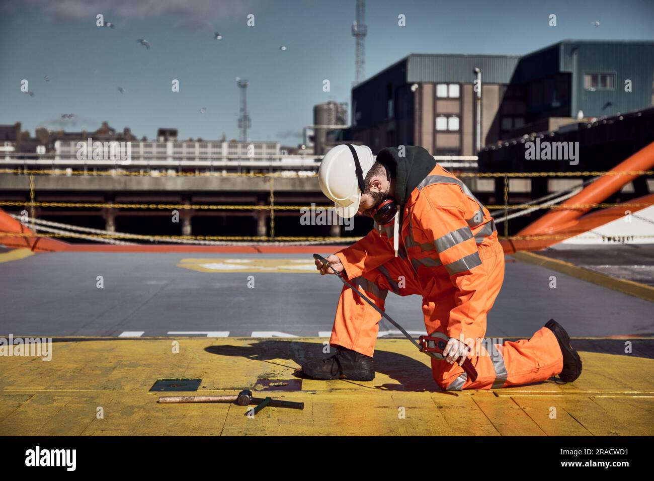 Giovane ingegnere offshore che suona serbatoio di carburante e olio sul ponte di carico sulla nave di rifornimento in porto. Foto Stock