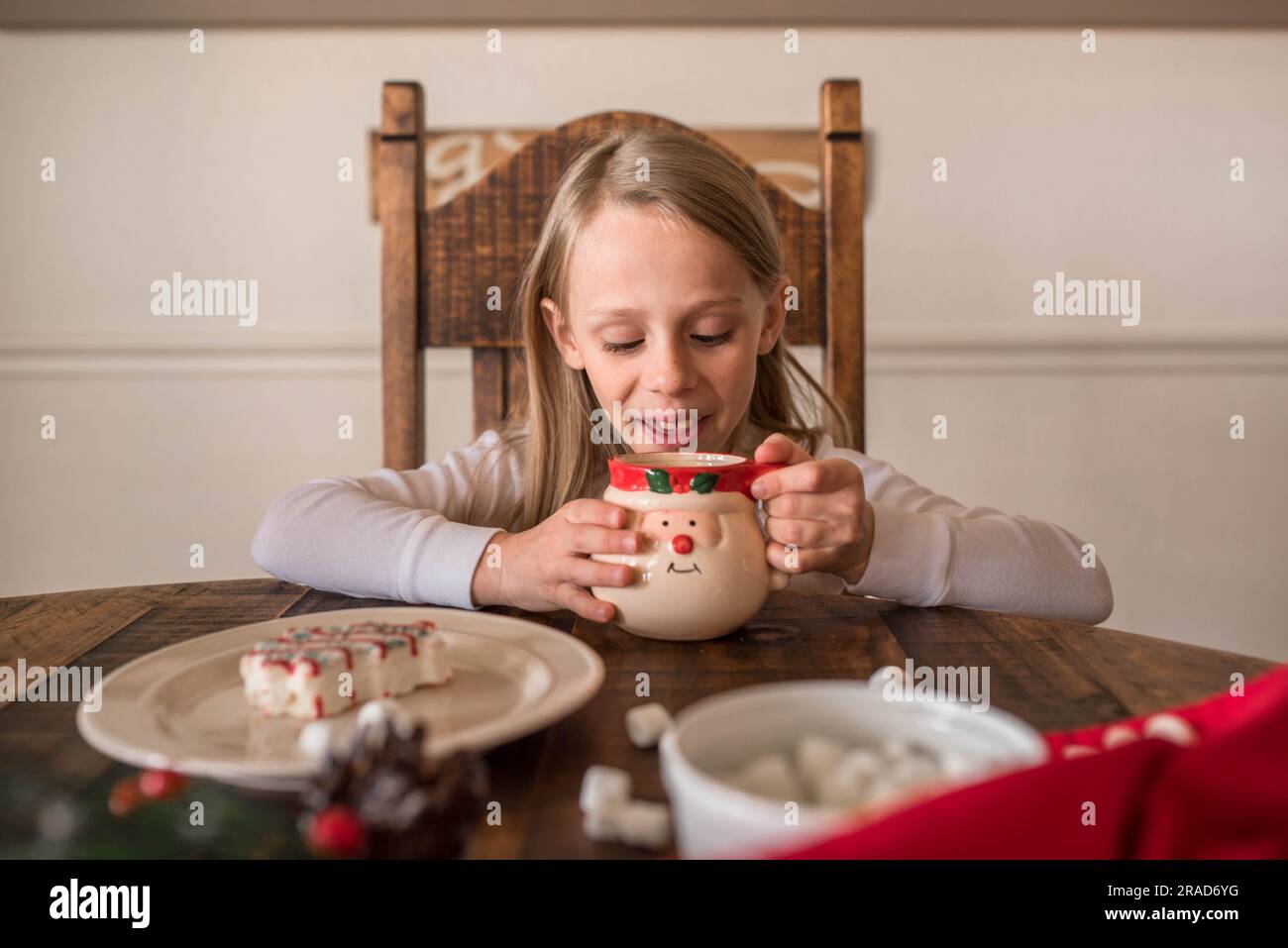 Ragazza che sta mangiando cioccolata calda con tema natalizio Foto Stock