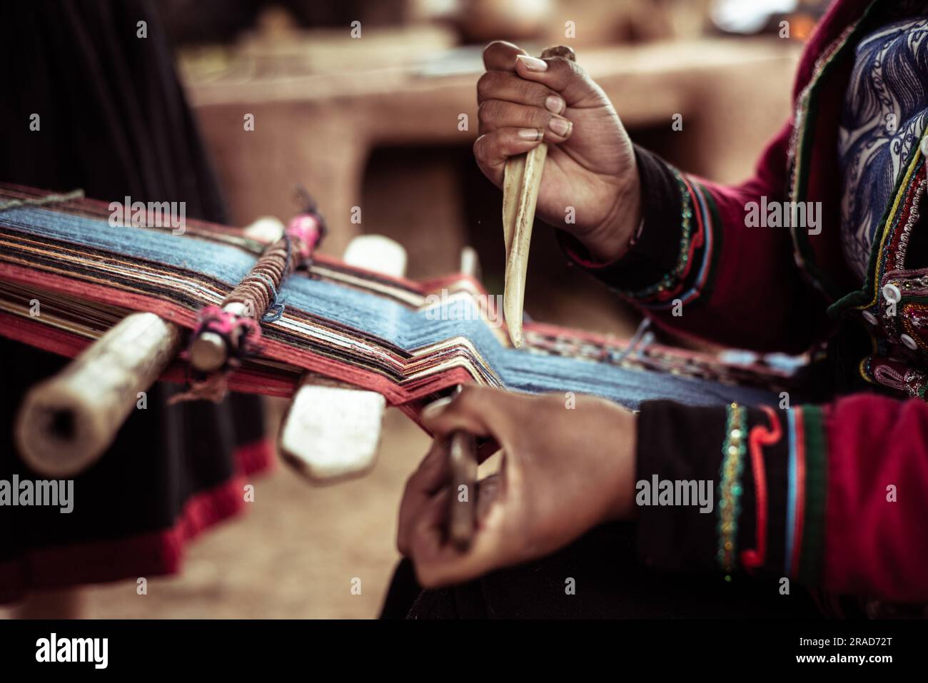 La donna locale in abiti tradizionali trita lana di alpaca con osso Foto Stock