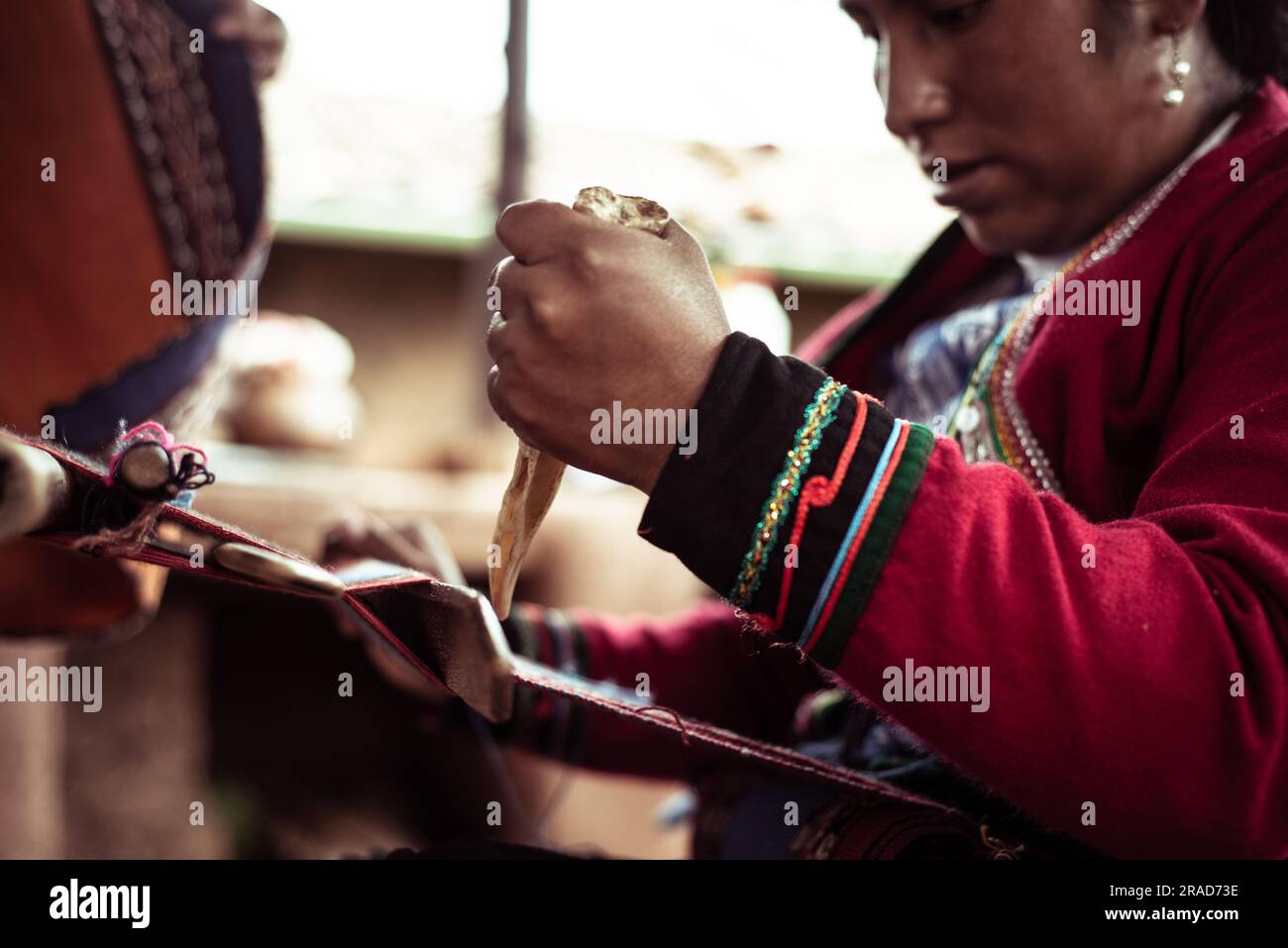 La donna locale in abiti tradizionali trita lana di alpaca con osso Foto Stock