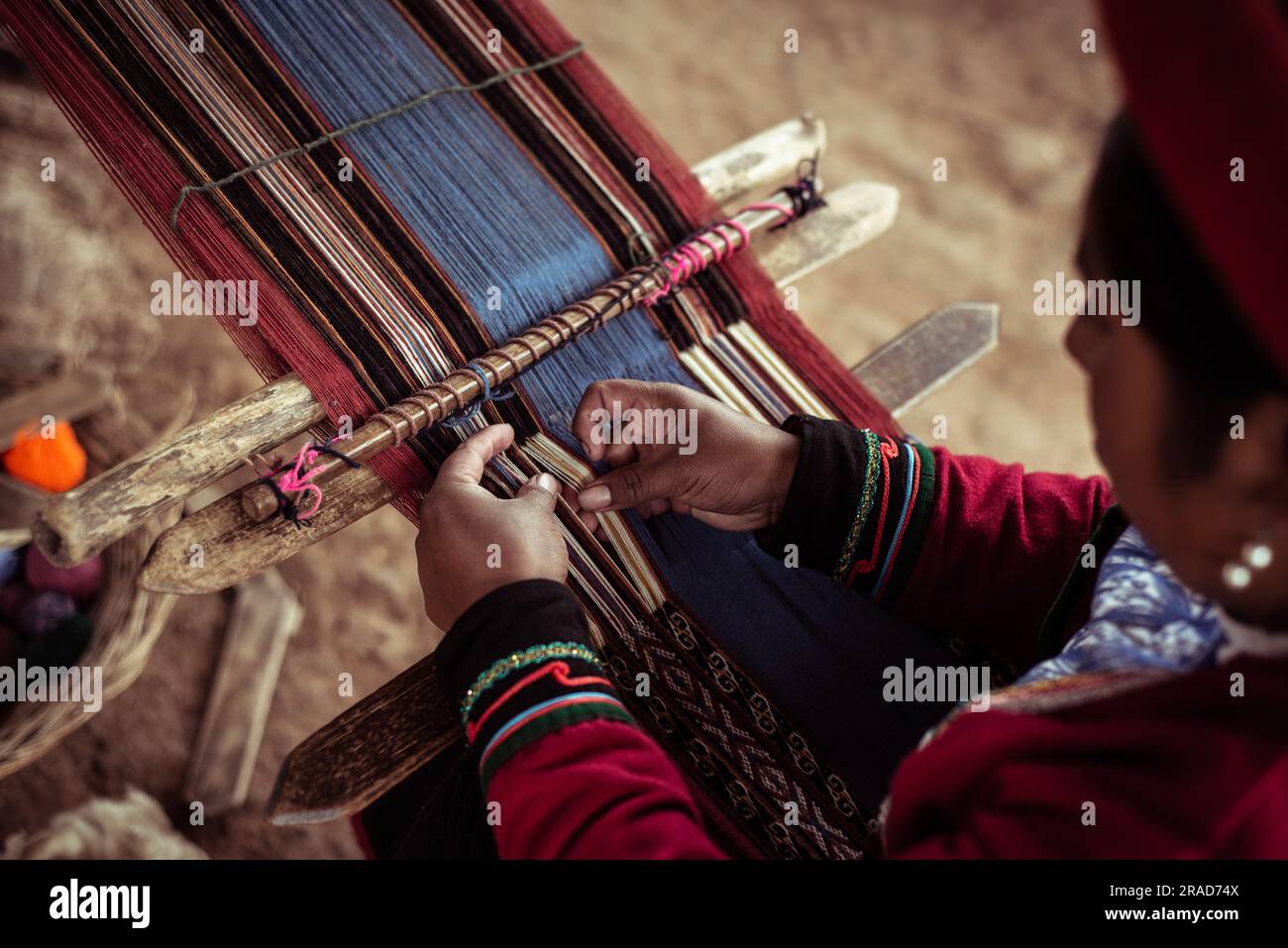 La donna locale in abiti tradizionali trita lana di alpaca con osso Foto Stock