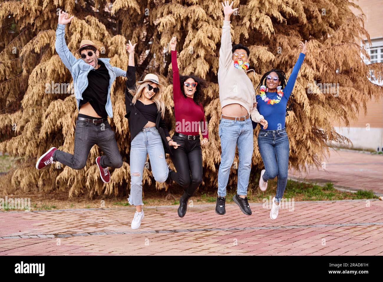Amici felici ed emozionati che saltano mentre fanno festa all'aperto. Festa, carnevale e amicizia. Foto Stock