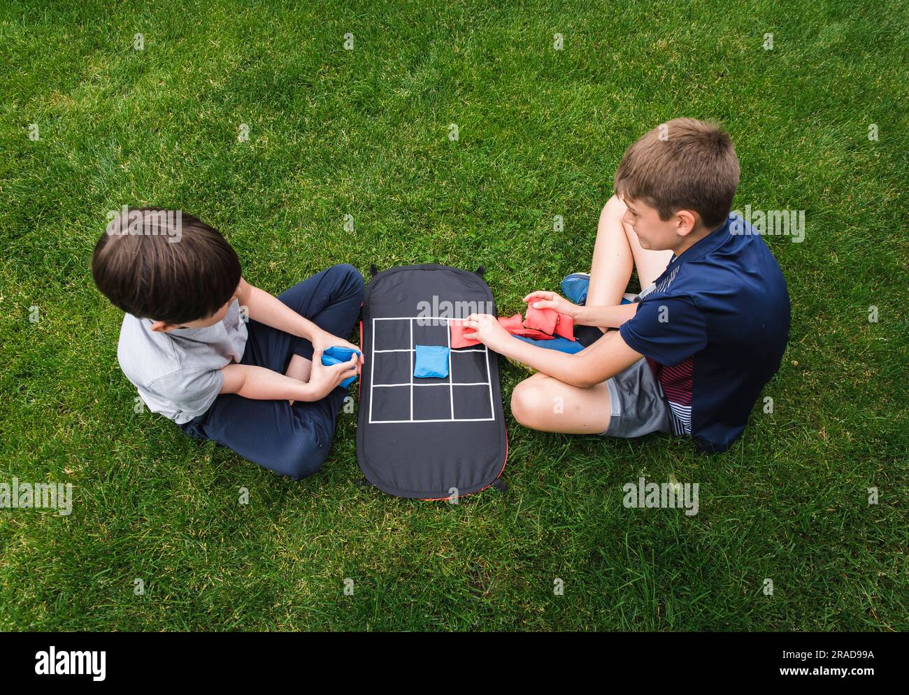 Tiro ad angolo alto di due ragazzi che giocano a tac toe game sull'erba. Foto Stock