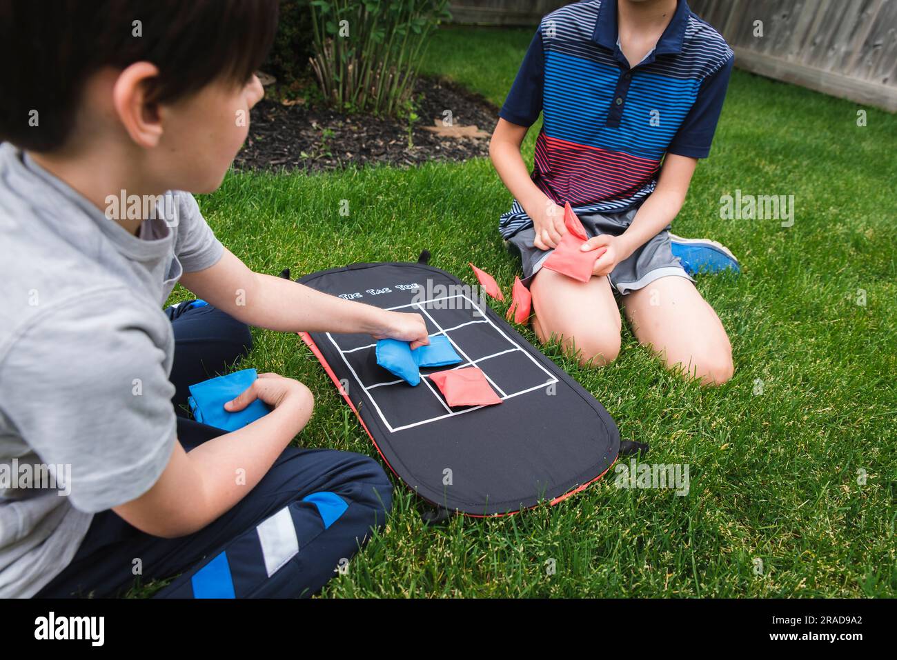 Due ragazzi che giocano a una partita a tac toe con sacchetti di fagioli sull'erba Foto Stock