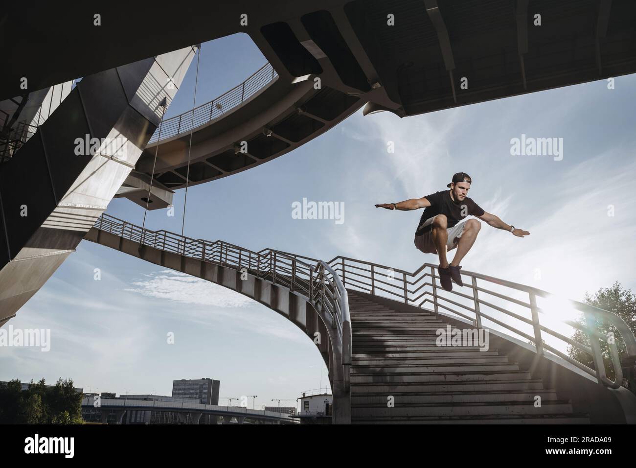 L'allenamento degli atleti del parkour in città. L'uomo esegue un grande salto freerunning attraverso le scale. Foto Stock
