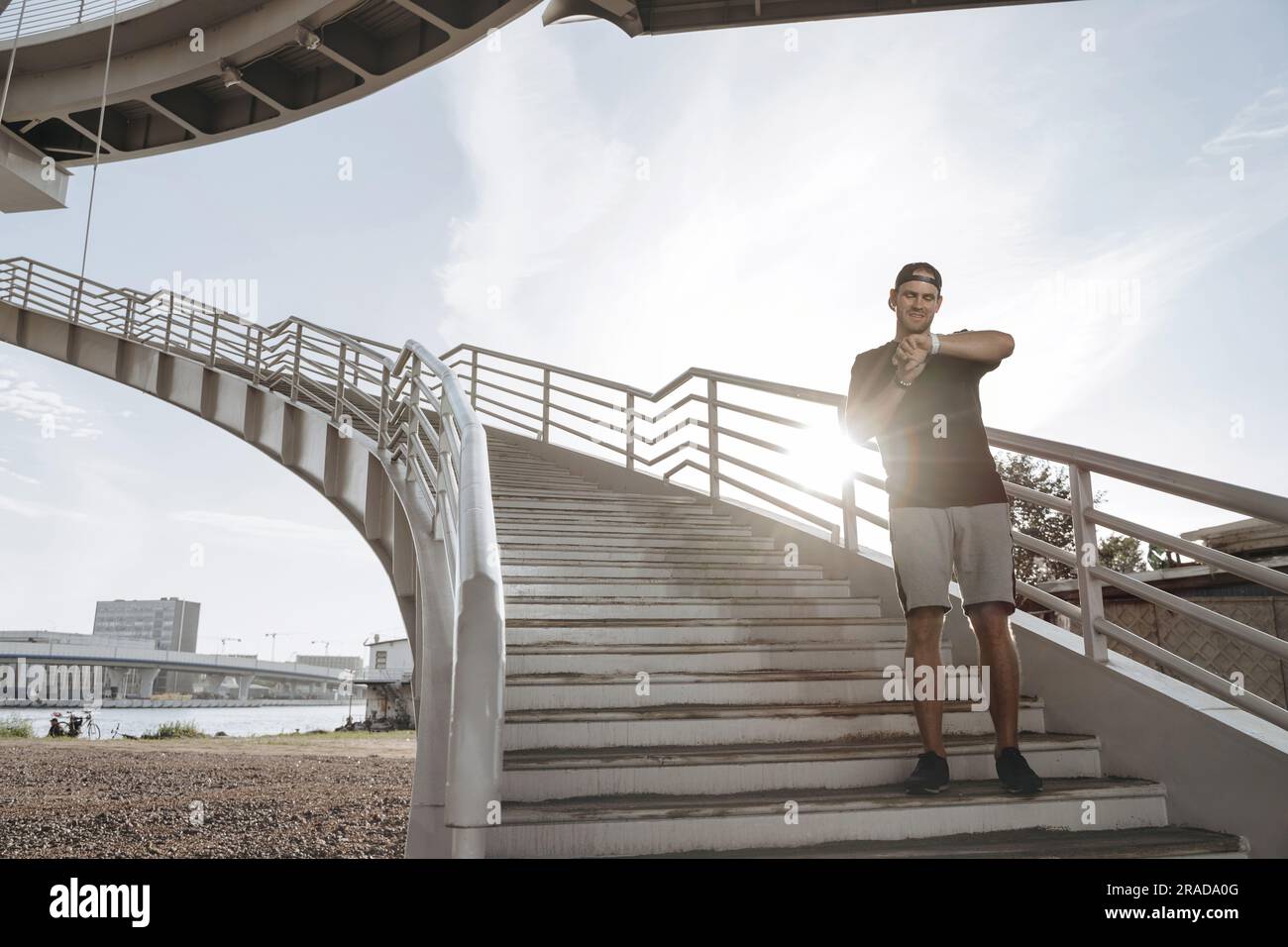 Un giovane atleta si alza sulle scale e guarda il suo orologio intelligente dopo un bel jogging. Foto Stock