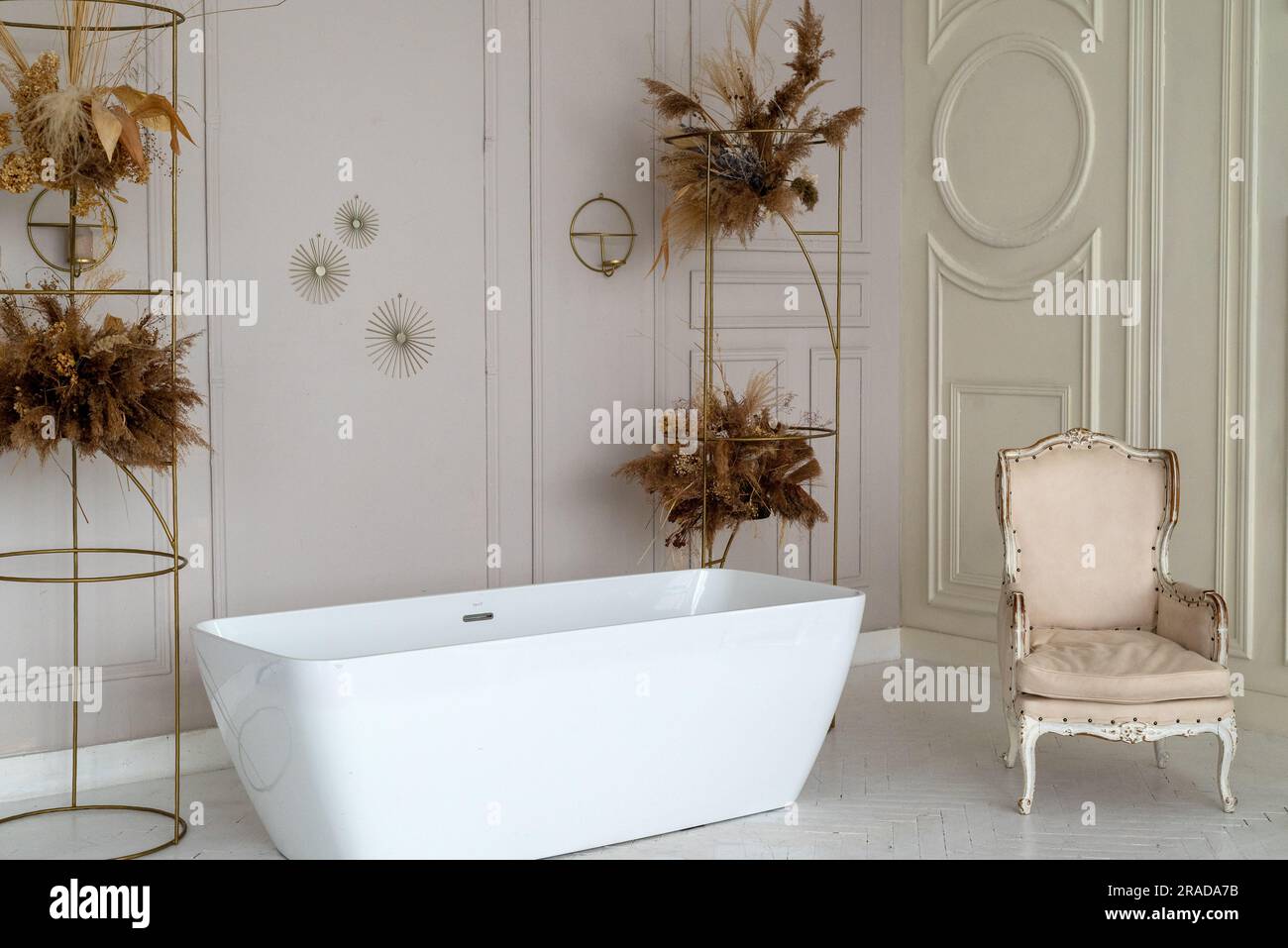 Elegante e luminoso interno del bagno con vasca moderna, fiori secchi, splendidi arredi e divano. Design per la casa. area foto Foto Stock