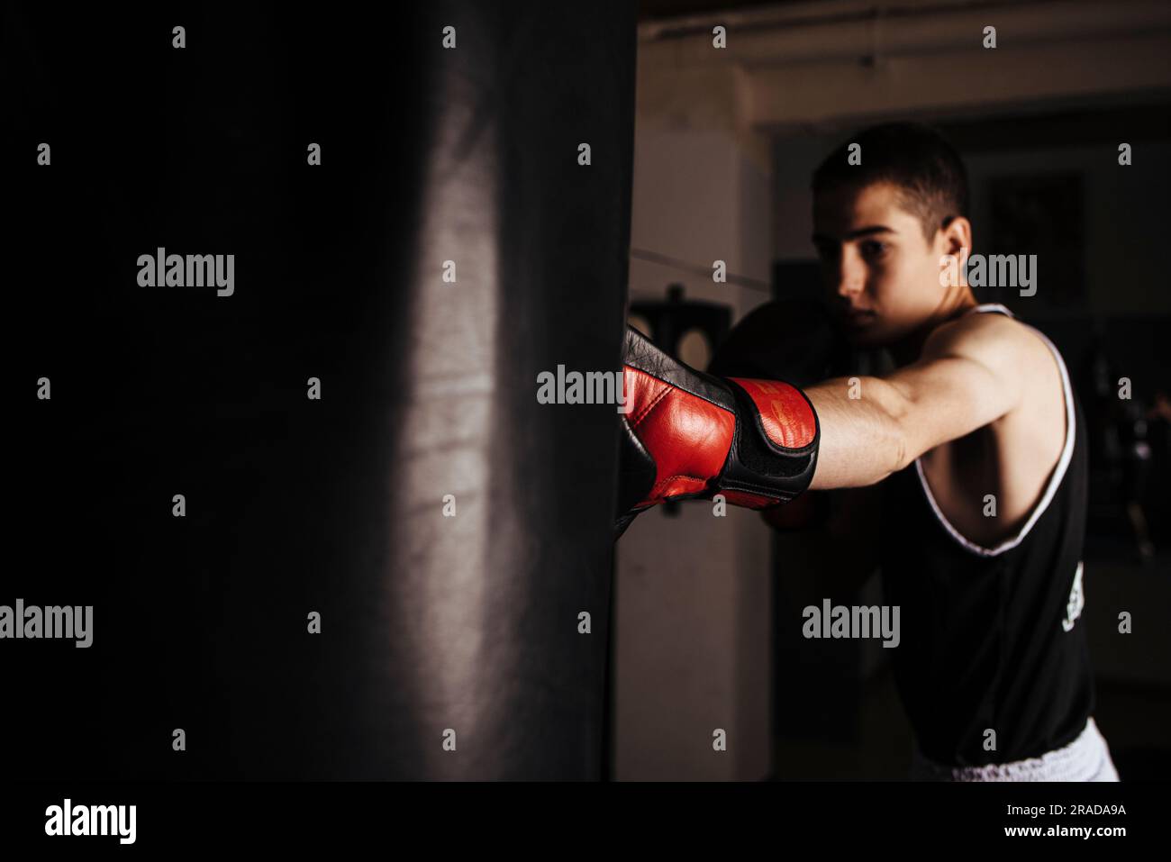 Pugile giovanotto che pratica una pugilata durante l'allenamento. Foto Stock