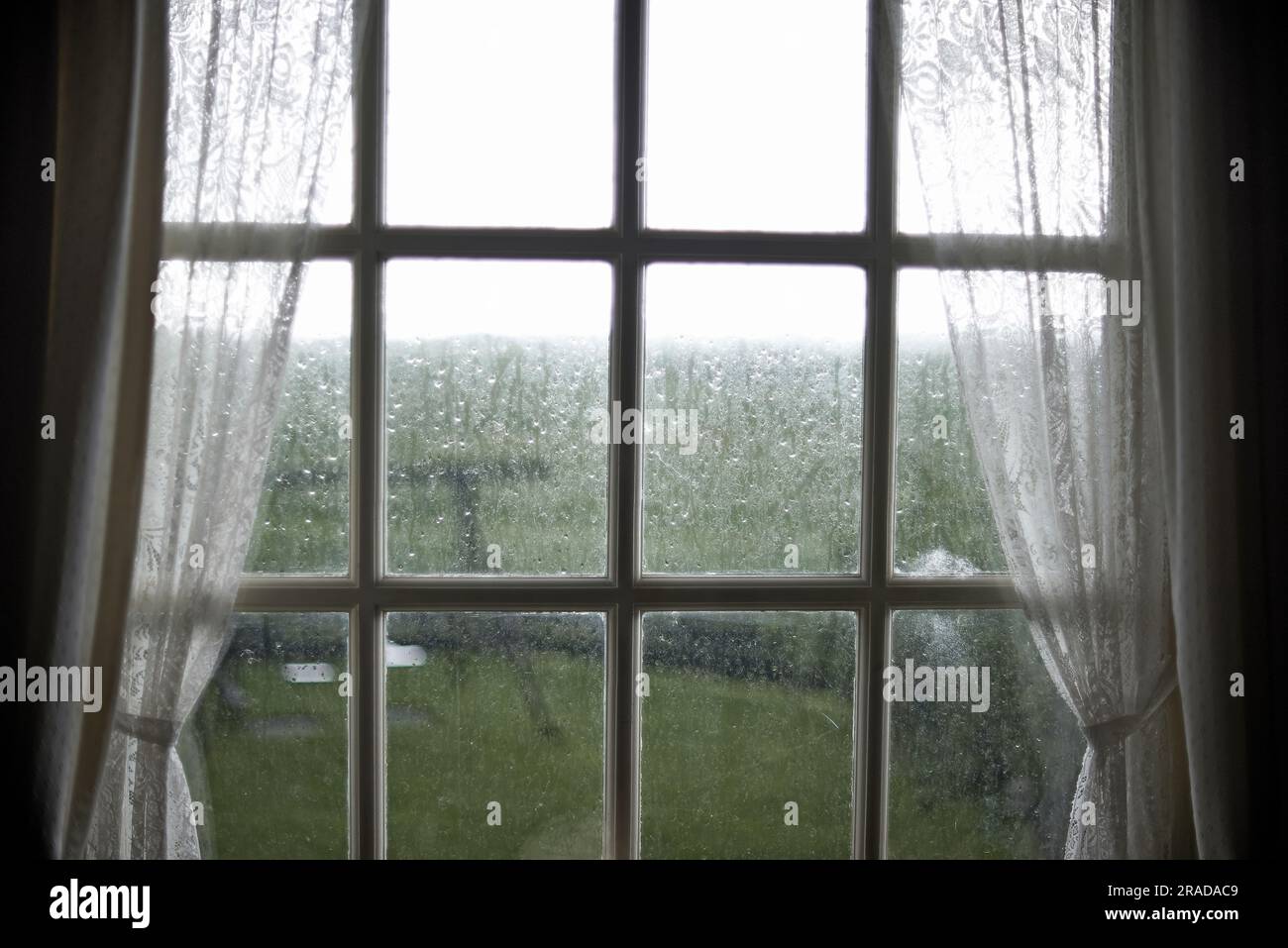 Primo piano di un vecchio telaio della finestra in legno con la pioggia all'esterno Foto Stock