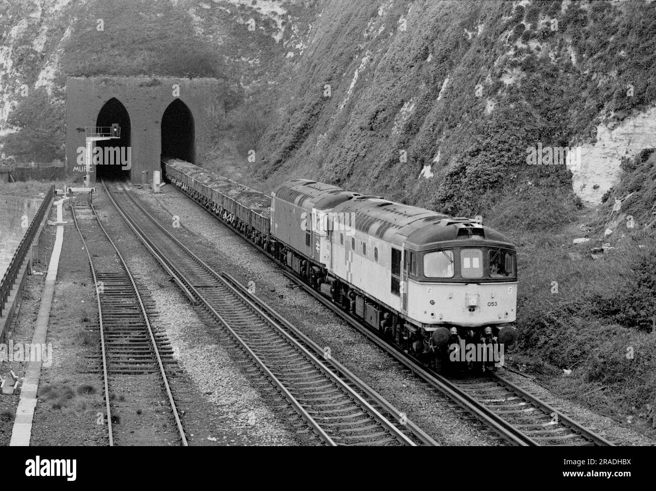 Un paio di locomotive diesel di classe 33, numero 33053 e 33040, a doppia rotta di un treno di rottami, emergono dal tunnel di Shakespeare Cliff vicino a dover l'8 aprile 1993. Foto Stock