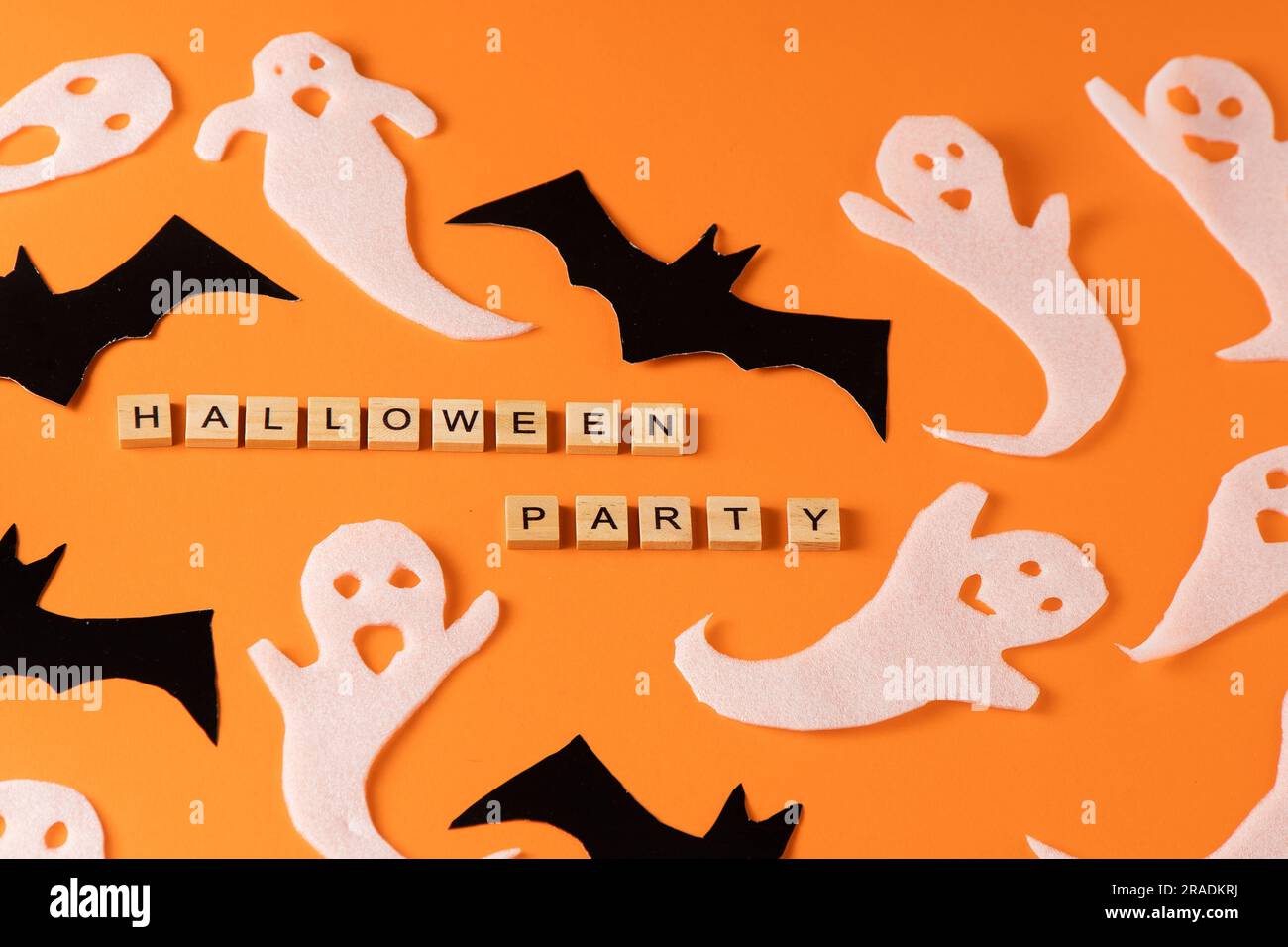 Fantasmi bianchi e mazza per la festa di Halloween. Immagine fantasma della carta di avvolgimento su sfondo arancione vista dall'alto. Fumetto Creepy Whisper. Fai-da-te fatto a mano. Impostare i caratteri boo. Parola frase di legno della lettera. Foto Stock