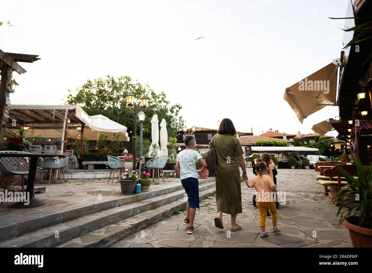 Vista posteriore di madre e bambini che camminano per la strada al tramonto Nessebar. Foto Stock