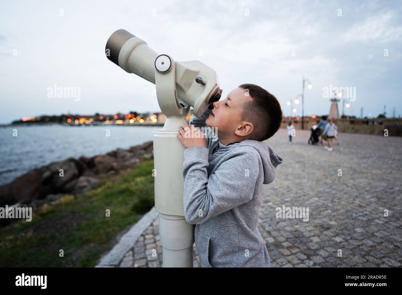 Il ragazzo guarda il mare attraverso un telescopio a gettoni la sera Nessebar. Foto Stock