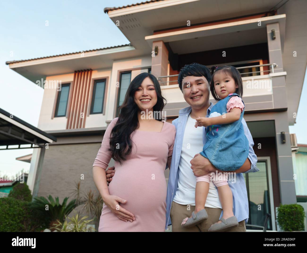 famiglia felice fuori casa, marito, moglie incinta e bambina Foto Stock