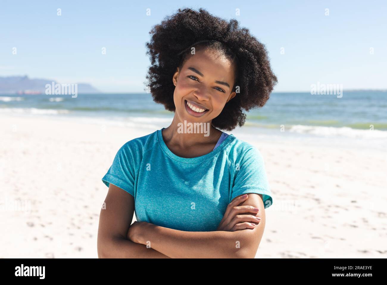 Ritratto di una felice donna afroamericana che guarda la macchina fotografica e sorride al sole sulla spiaggia Foto Stock