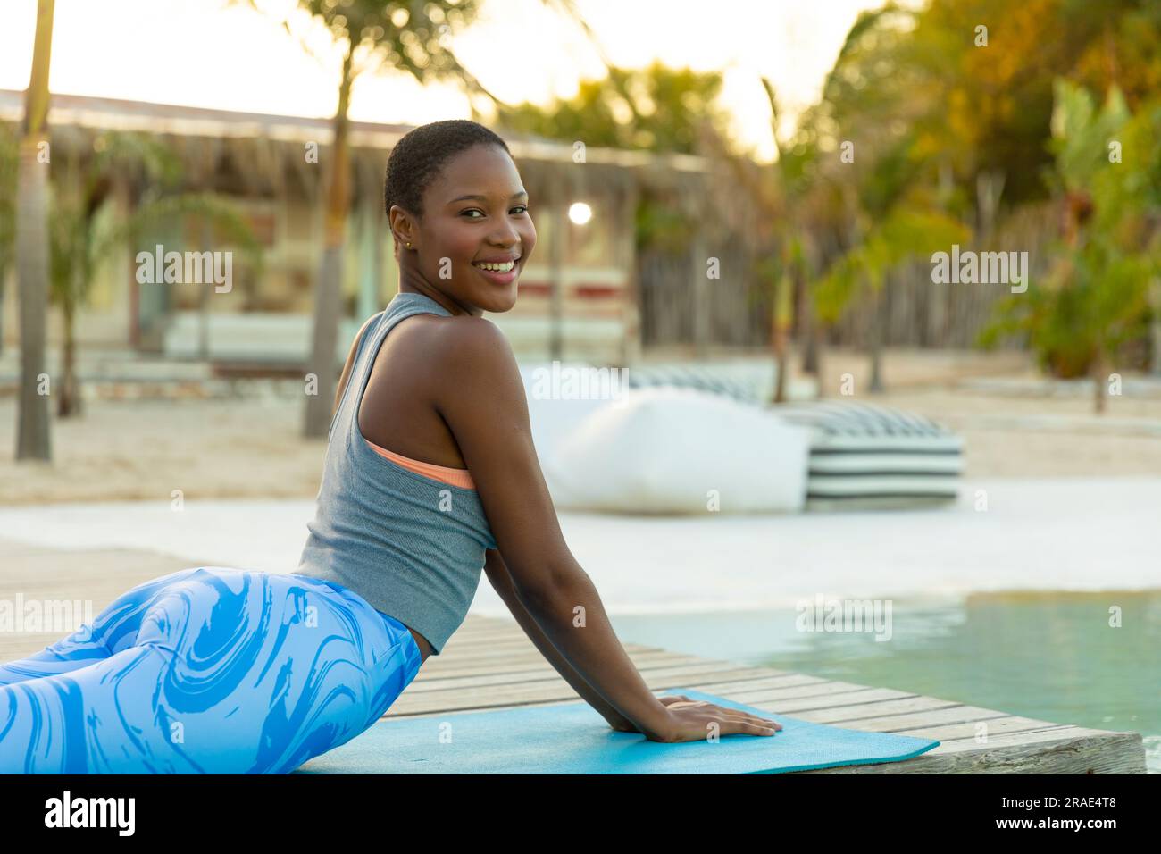 Ritratto di una felice donna afroamericana che pratica yoga, si allunga in piscina sulla spiaggia, copia spazio Foto Stock
