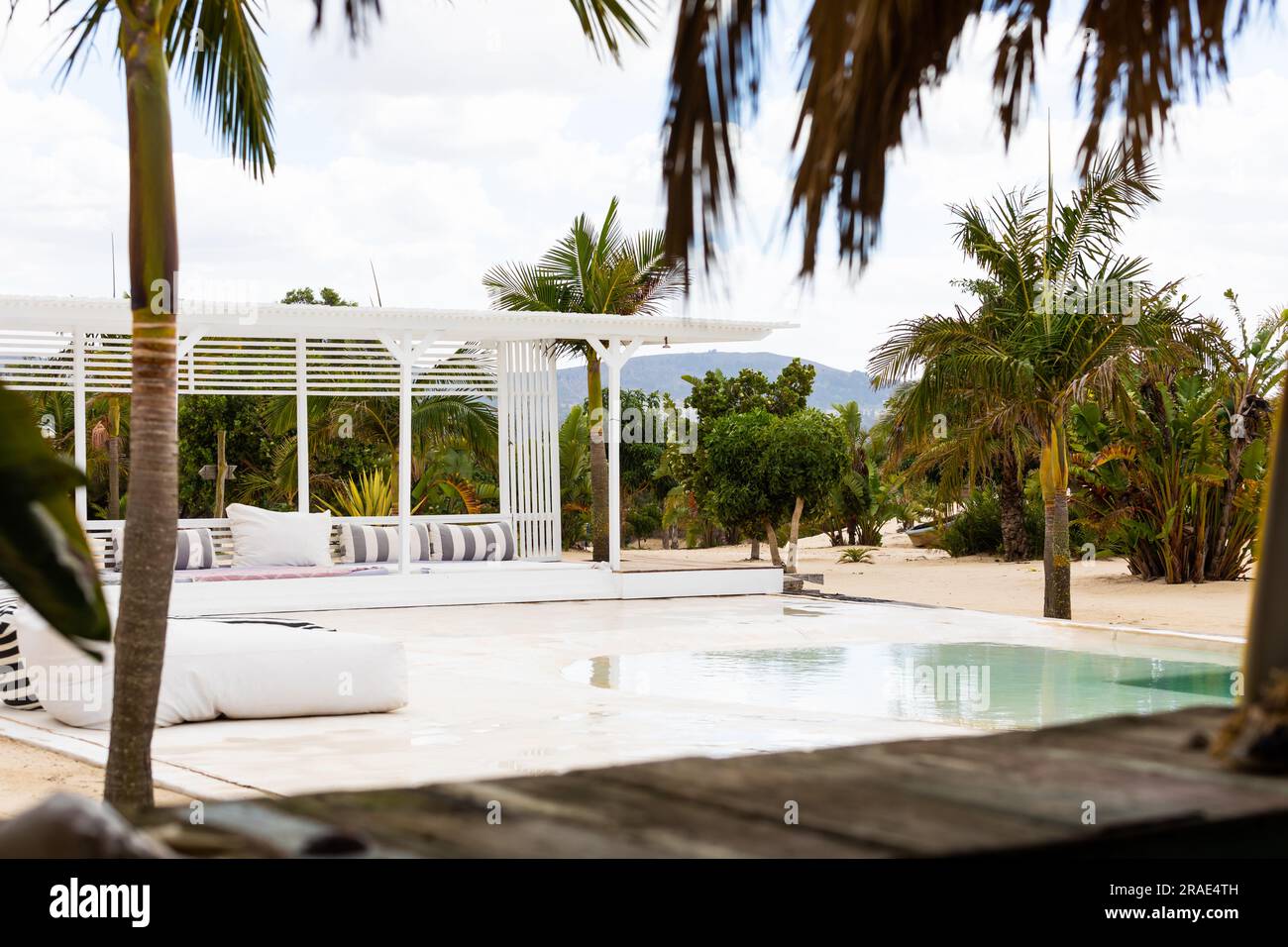 Piscina e terrazza con mobili all'aperto e palme presso il resort tropicale sulla spiaggia, spazio fotocopie Foto Stock