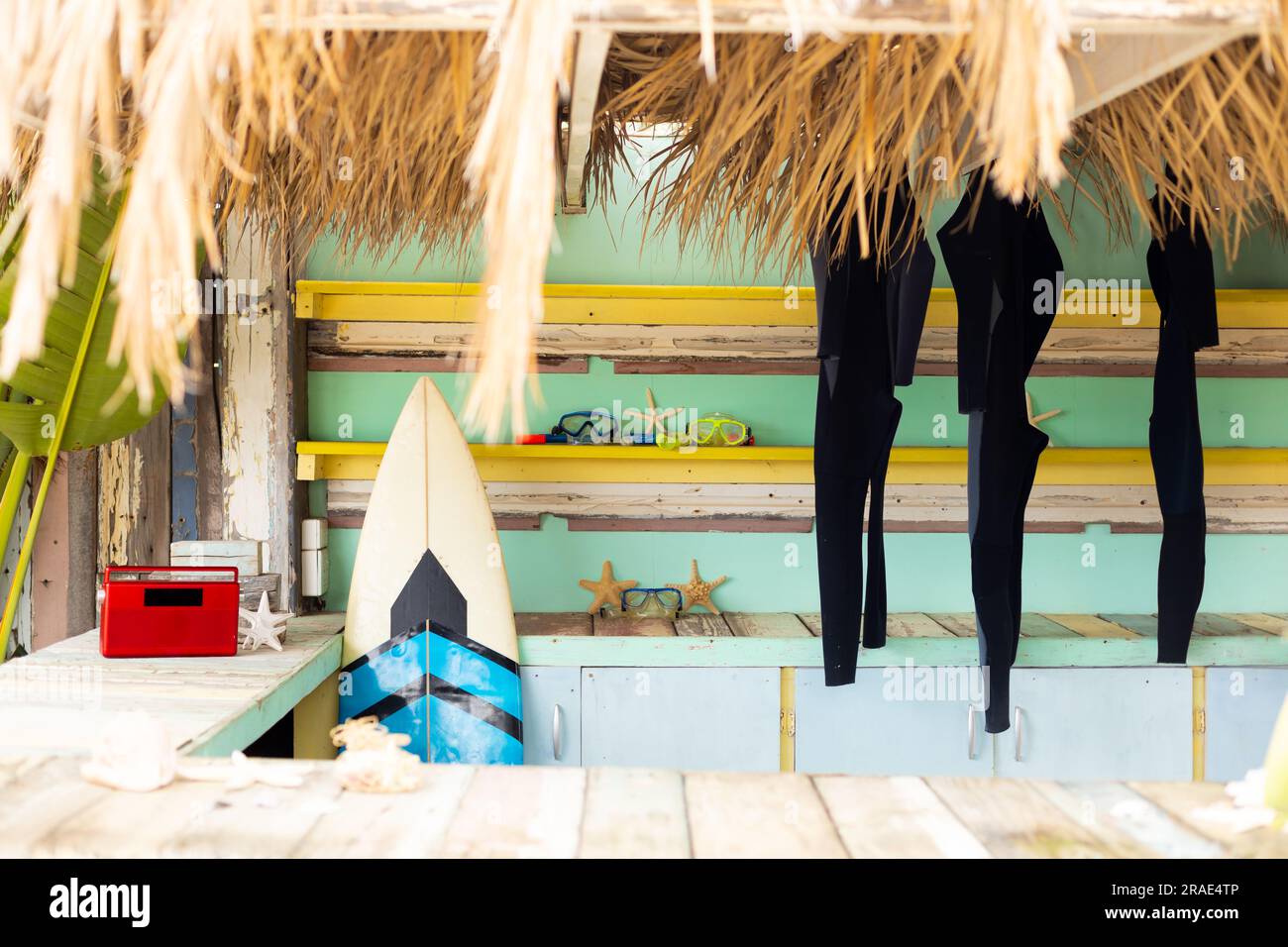 Bancone del soleggiato negozio di noleggio surf sulla spiaggia con radio, tavola da surf e muta appesa Foto Stock
