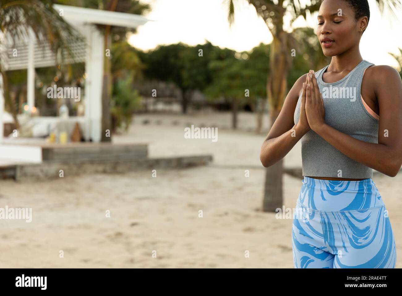 Felice donna afro-americana che pratica meditazione yoga in spiaggia al tramonto Foto Stock
