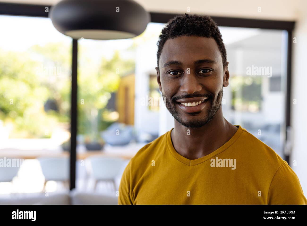 Ritratto di un uomo afro-americano felice che guarda la macchina fotografica e sorride a casa Foto Stock