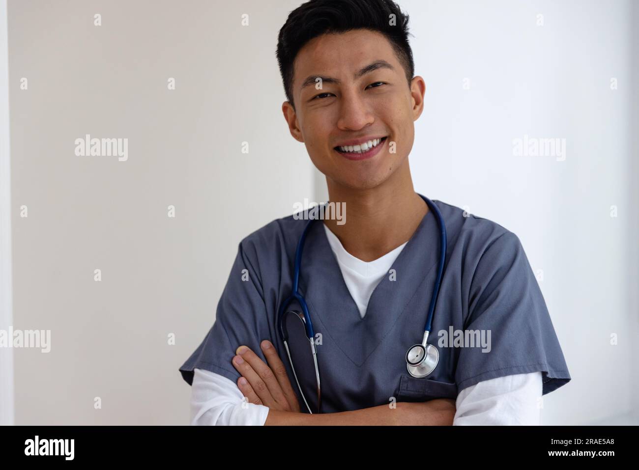 Ritratto di un medico maschio asiatico felice contro il muro bianco Foto Stock