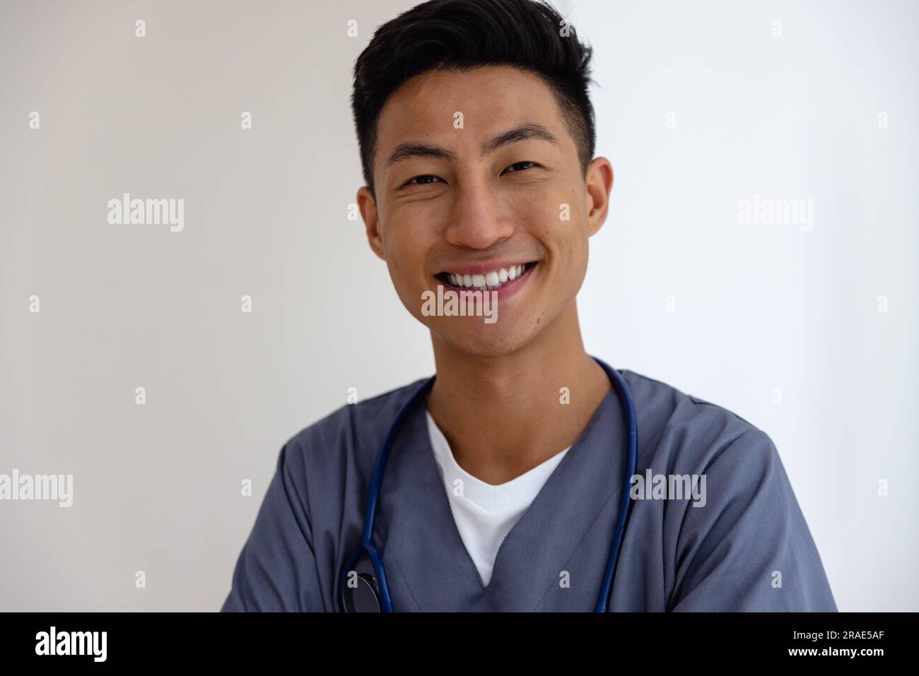 Ritratto di un medico maschio asiatico felice contro il muro bianco Foto Stock