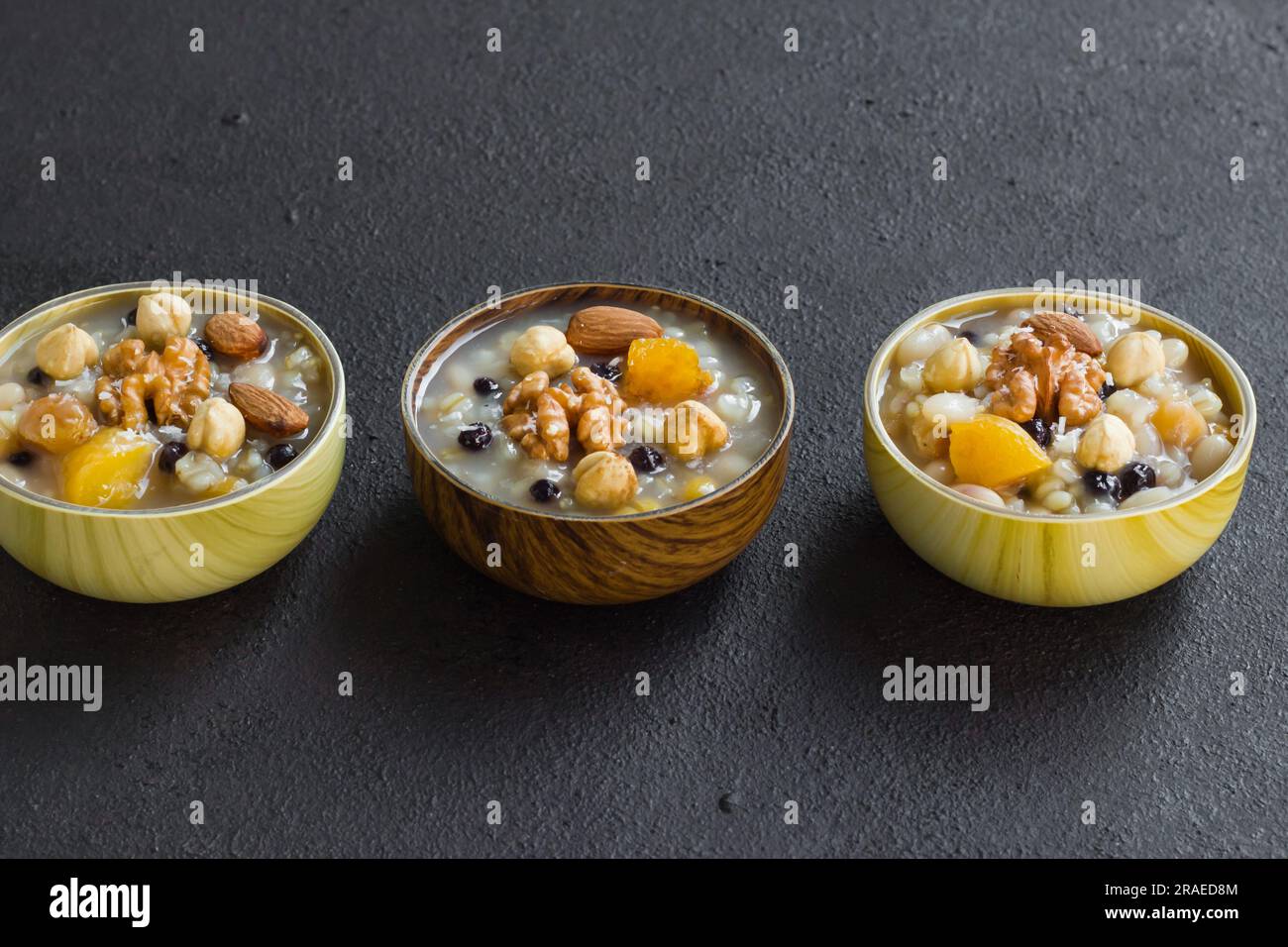 Tradizionale dessert turco Ashure o Noah Puding, realizzato in ciotole di bambù su superficie nera Foto Stock