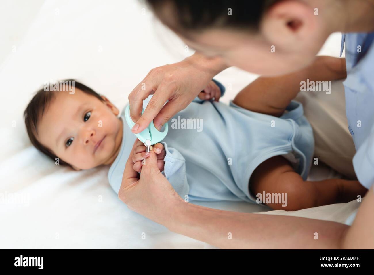 la madre taglia le unghie delle mani del neonato con le forbici per unghie. Foto Stock