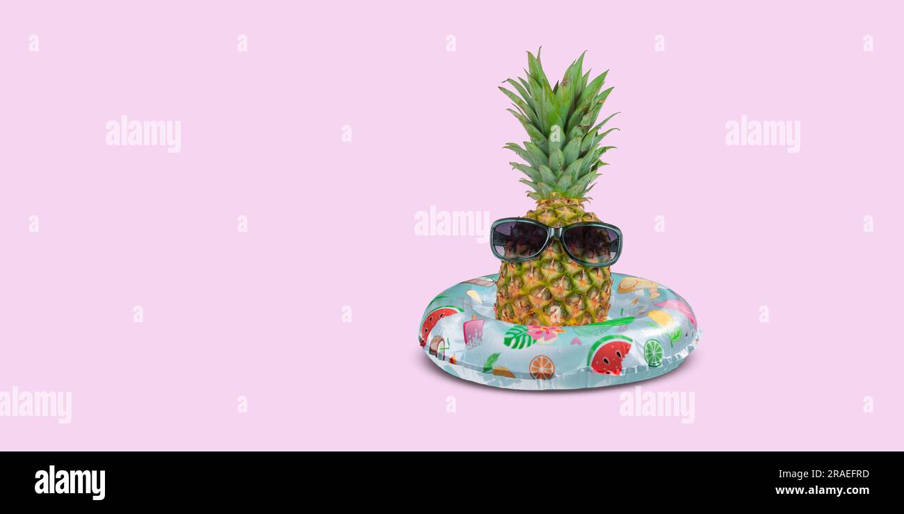 Ananas con occhiali da sole nell'anello gonfiabile su sfondo rosa. Foto Stock