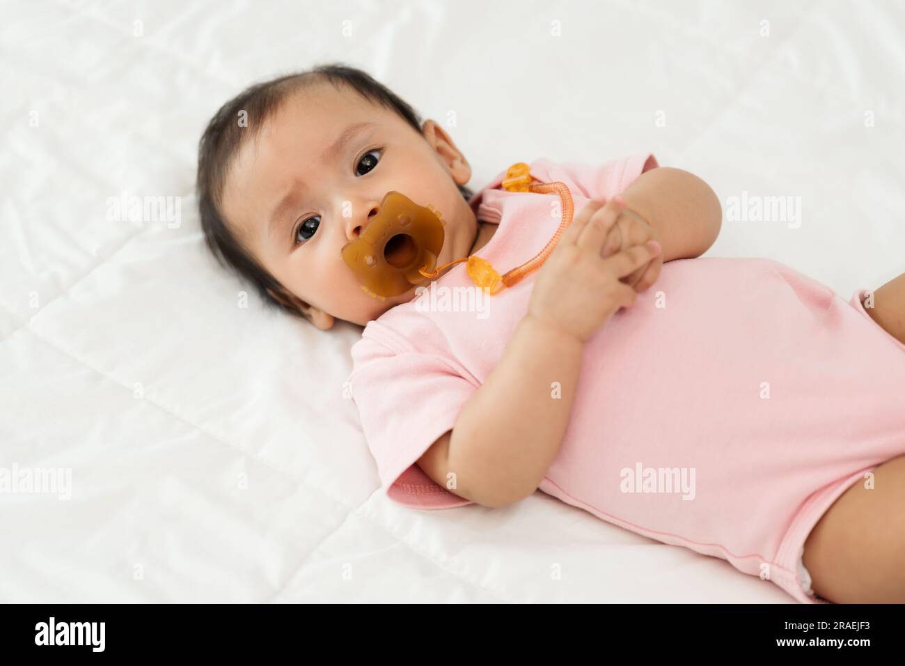 la neonata succhia con il succhietto su un letto Foto Stock