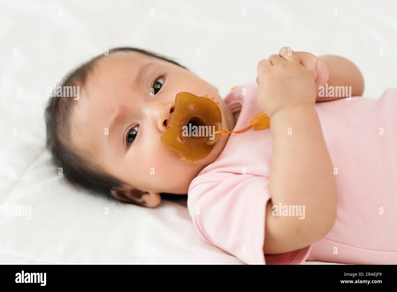 la neonata succhia con il succhietto su un letto Foto Stock