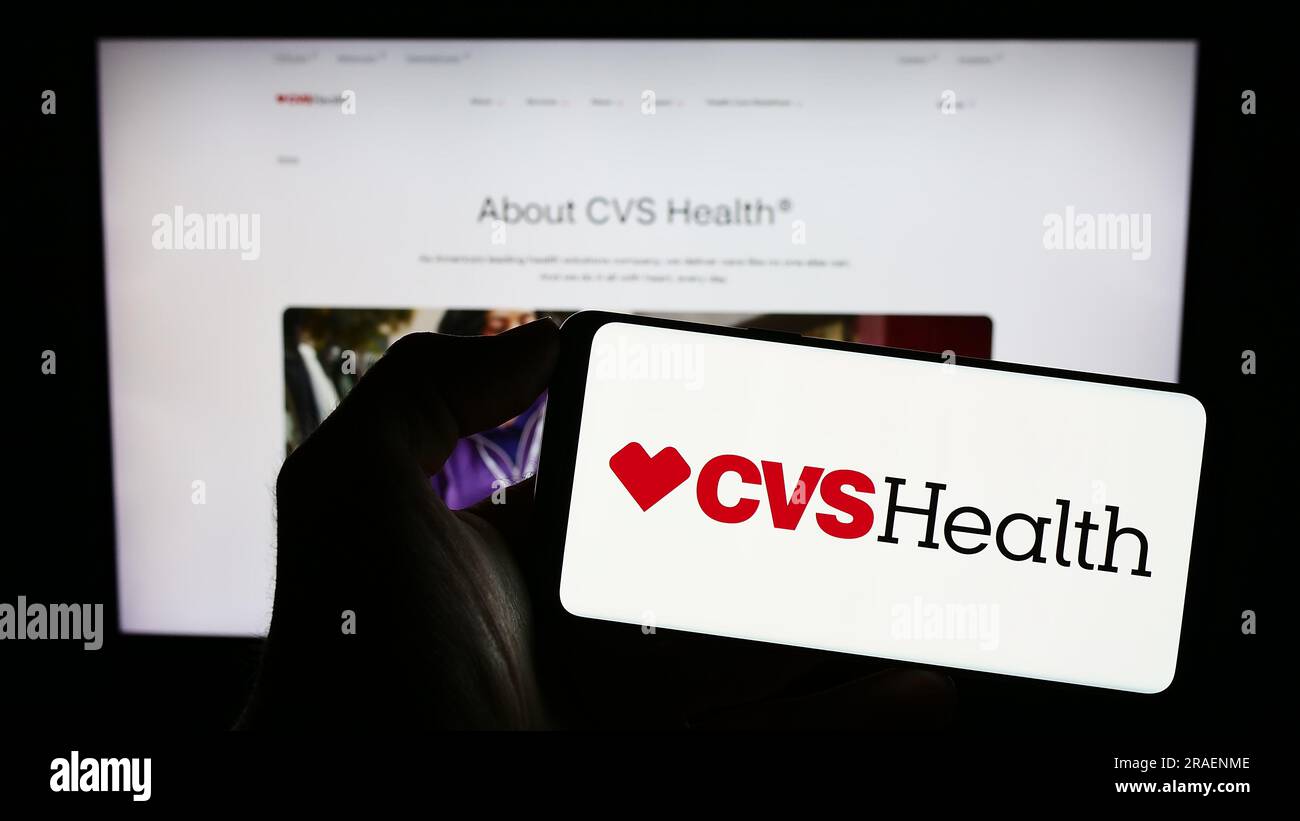 Persona in possesso di cellulare con logo della società sanitaria statunitense CVS Health Corporation sullo schermo di fronte alla pagina Web aziendale. Concentrarsi sul display del telefono. Foto Stock