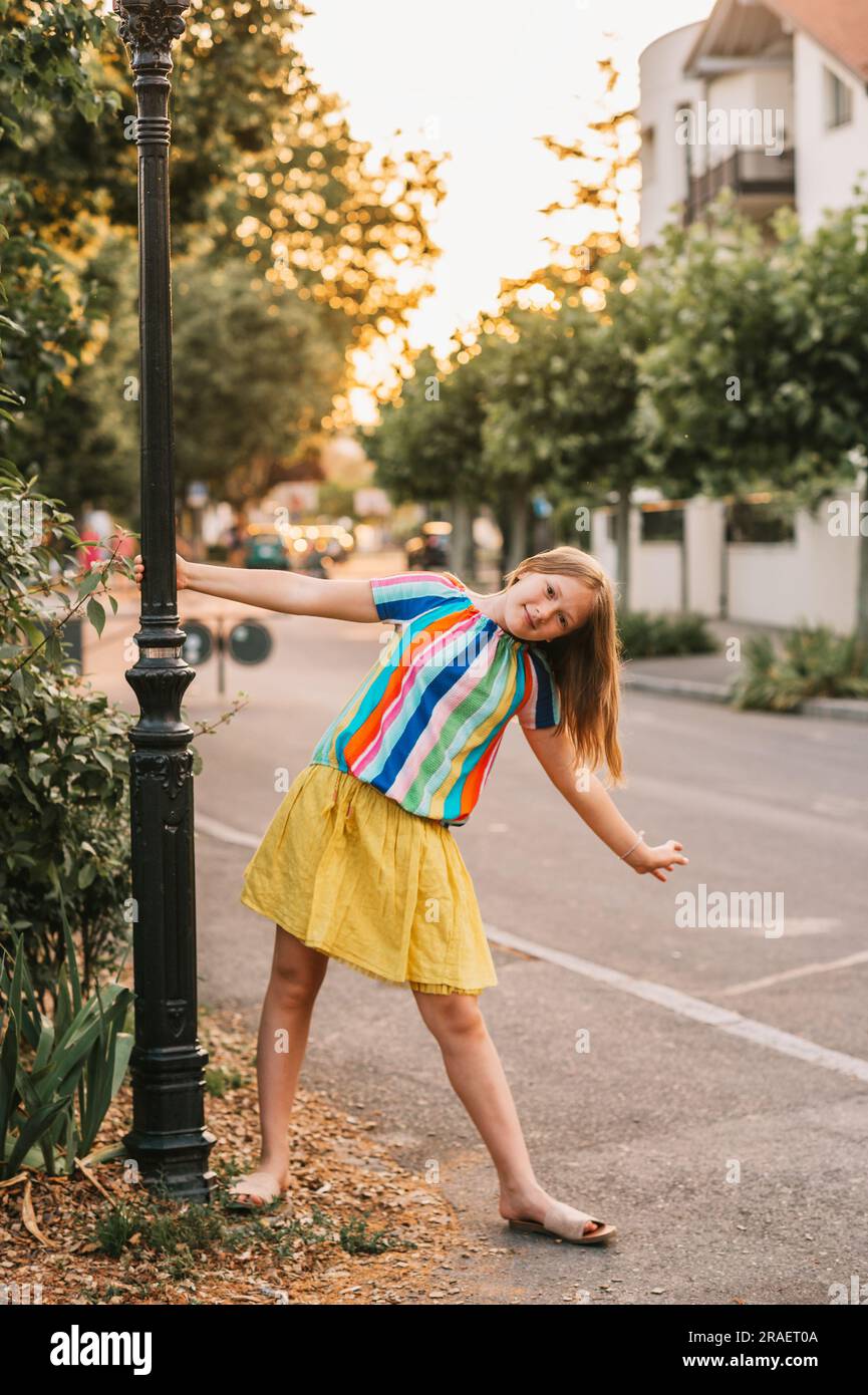 Ritratto estivo di una bambina che posa all'aperto, indossa una gonna gialla e una blusa colorata Foto Stock