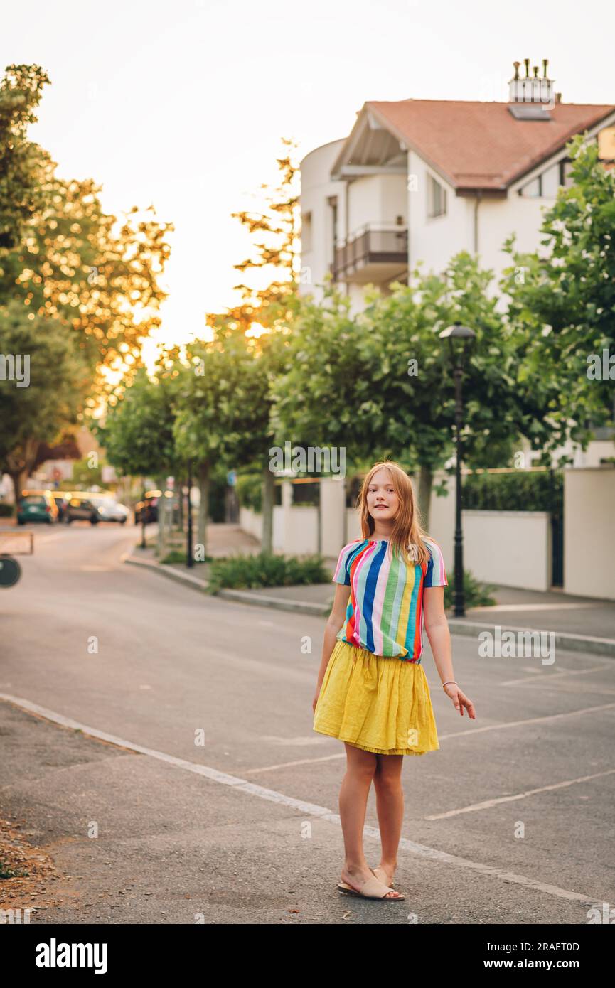 Ritratto estivo di una bambina che posa all'aperto, indossa una gonna gialla e una blusa colorata Foto Stock