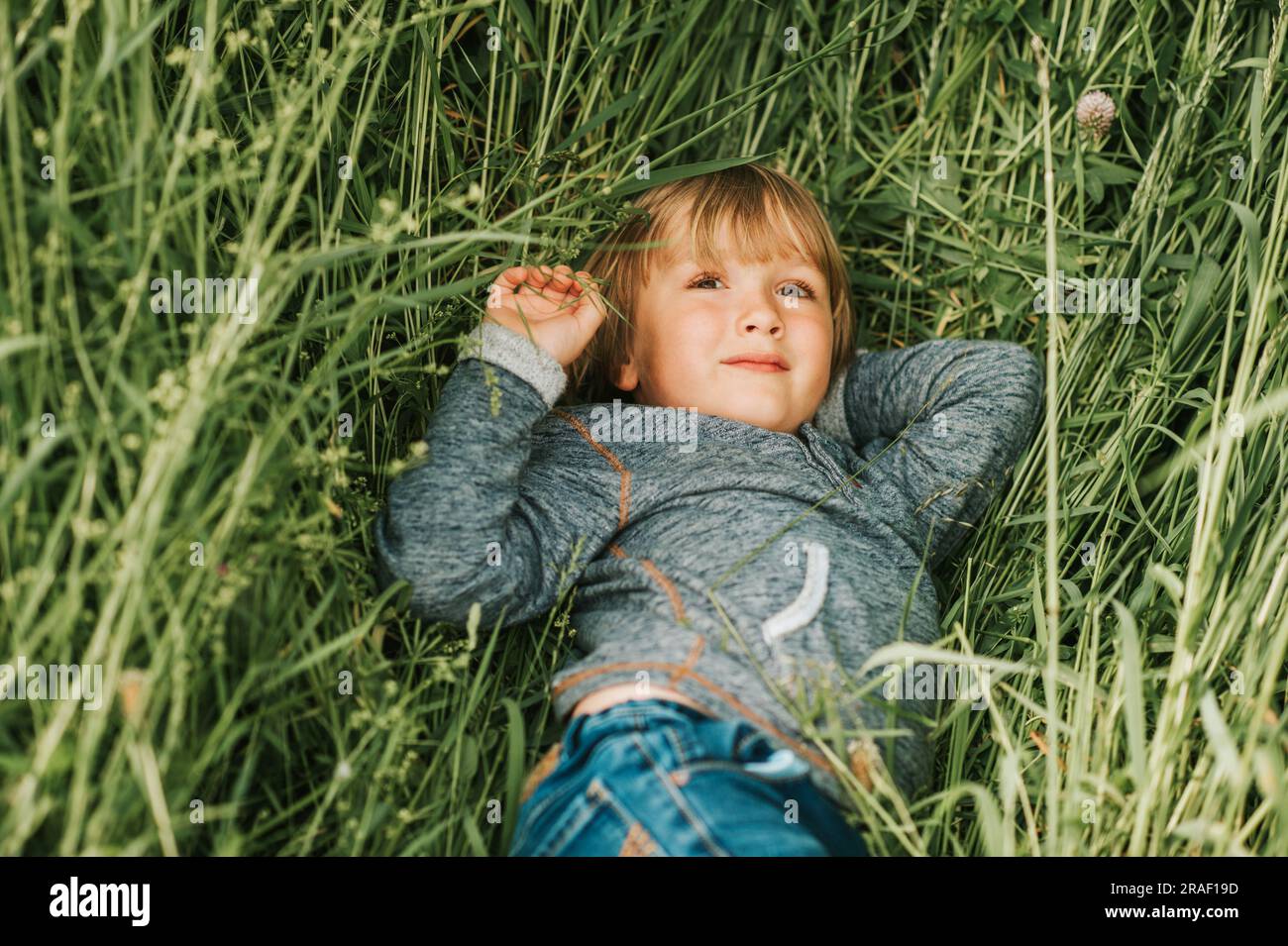 Ritratto sincero di un adorabile ragazzino di 4-5 anni, che indossa una felpa con cappuccio blu Foto Stock