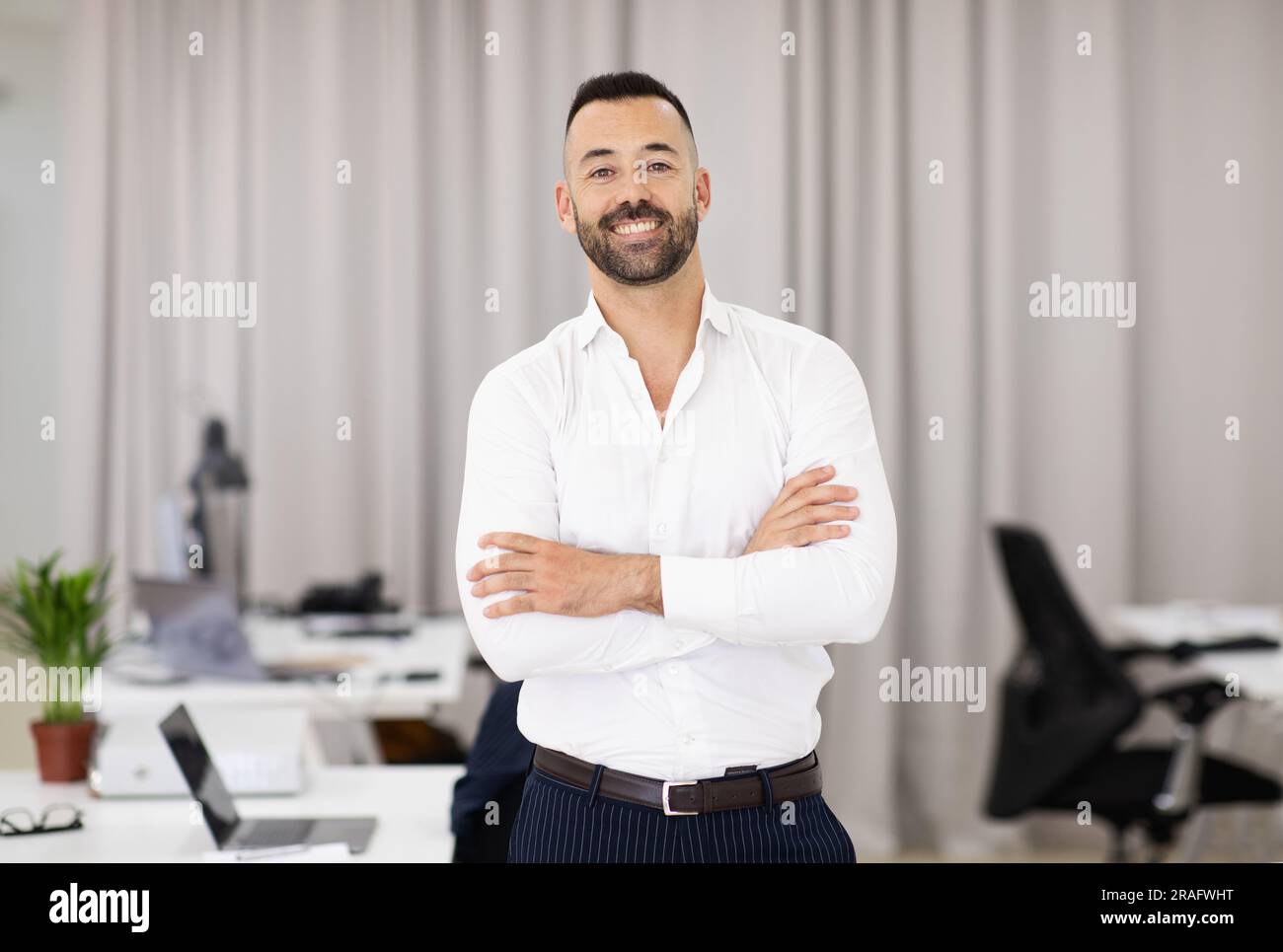 Allegro sicuro adulto europeo attraente uomo in camicia bianca con barba e braccia incrociate sul petto Foto Stock