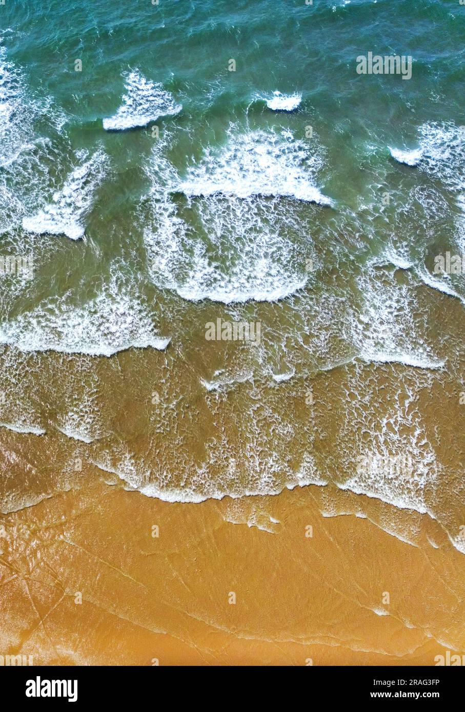 Vista aerea delle onde su una spiaggia sabbiosa. Niente persone. Sfondi. Foto Stock