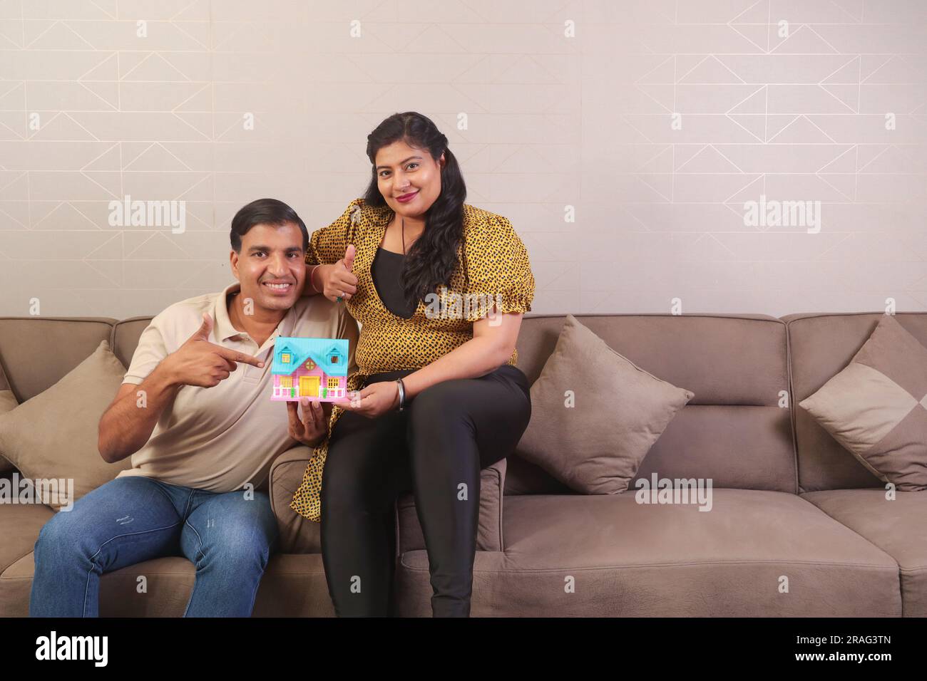 Felice coppia indiana seduta su un divano. La scelta di casa dei sogni diventa realtà. investimento nell'acquisto di una casa Foto Stock